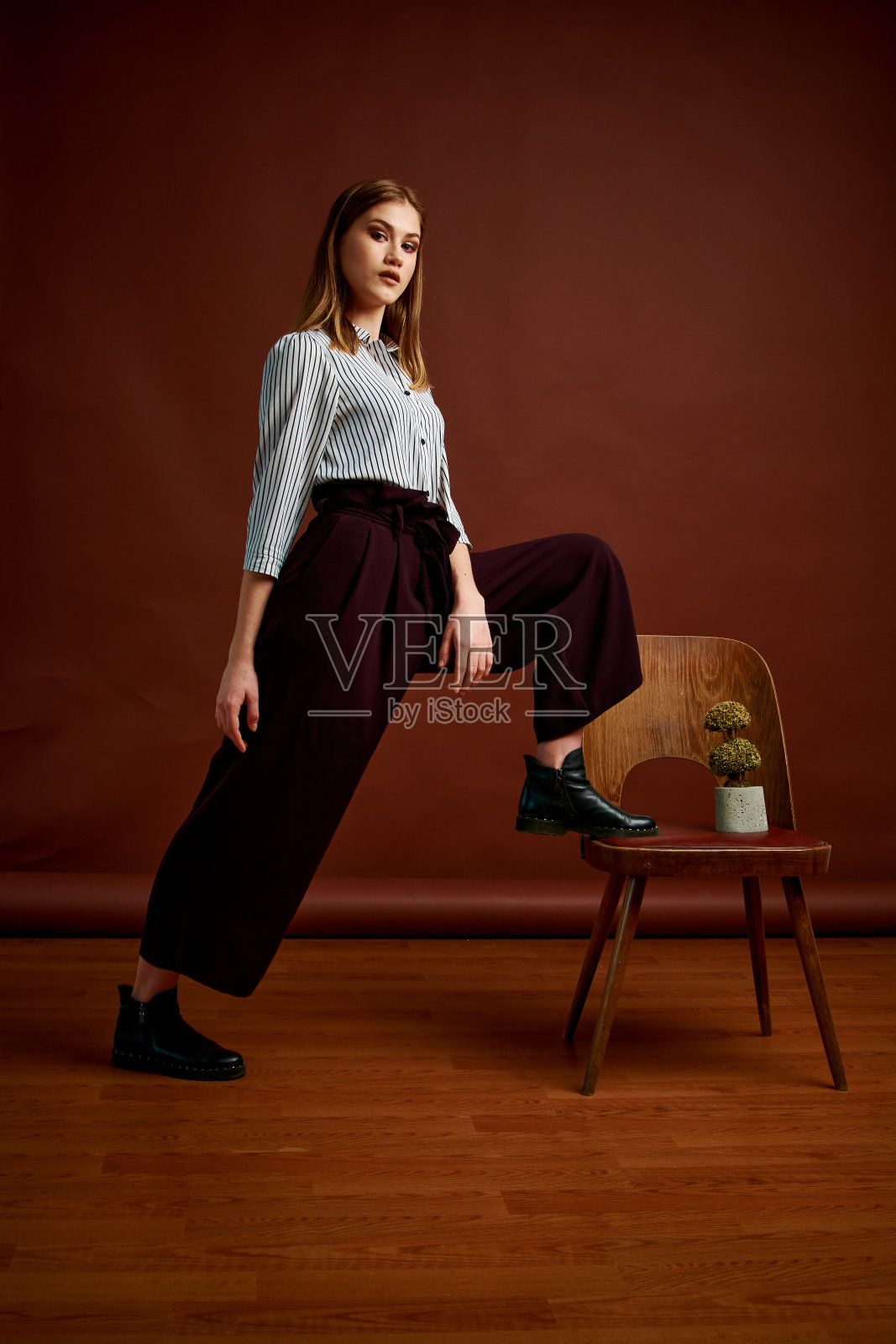 漂亮的年轻女性,穿着经典的套装,黑色的鞋子和灰色的外套。古董椅子。女人的衣服。照片摄影图片