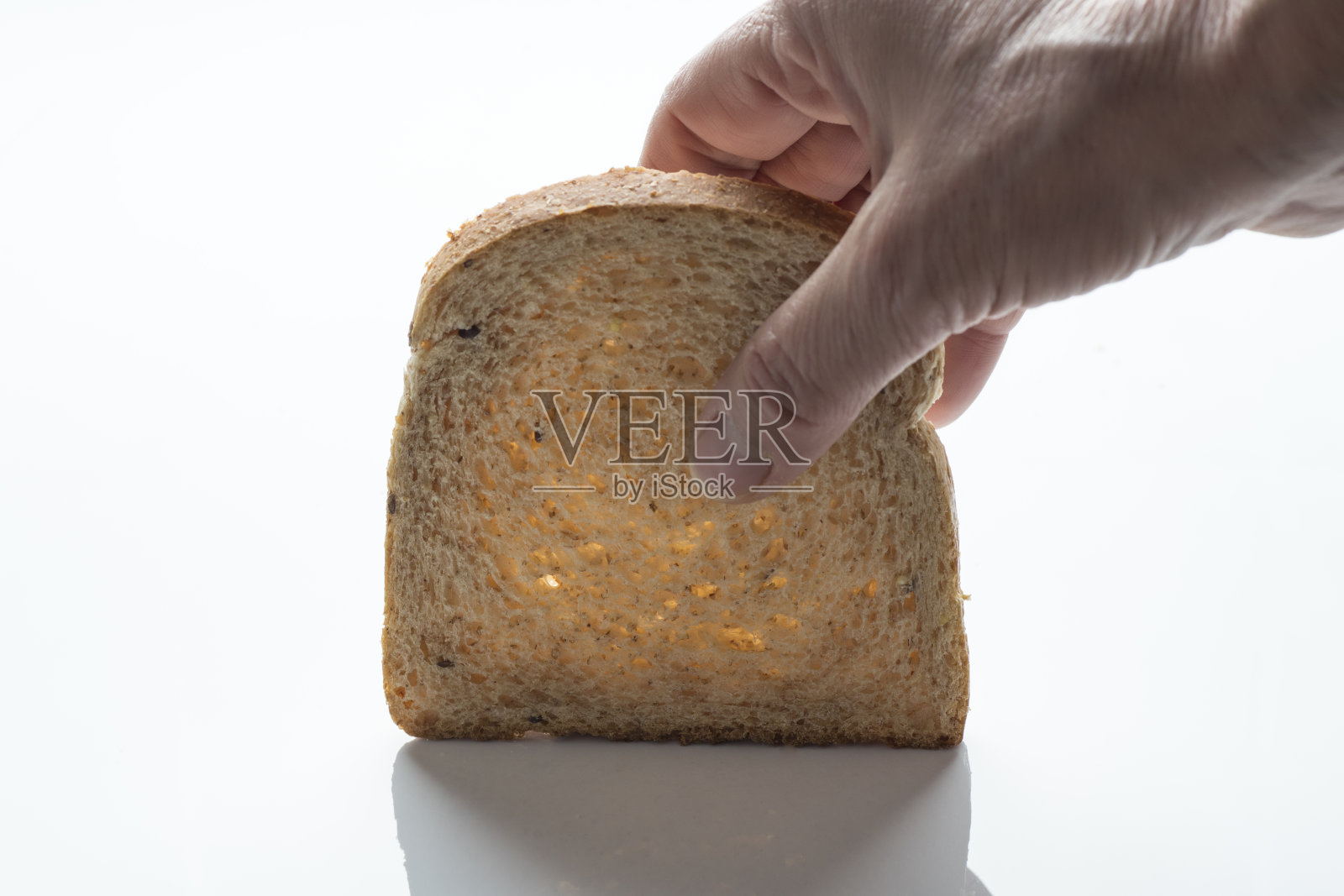 一片带有谷物和种子的切片面包,在白色的表面上有反射照片摄影图片