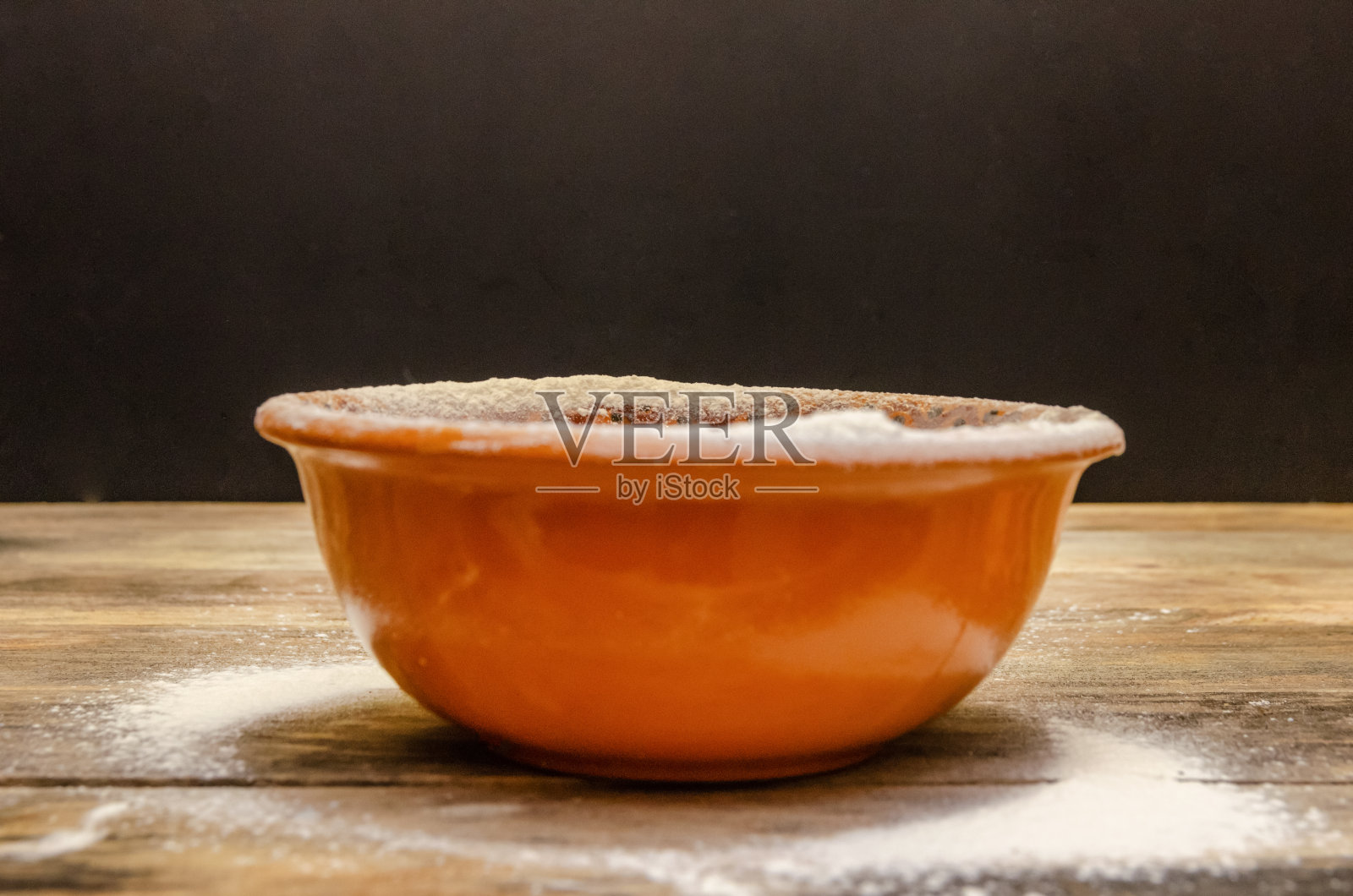 木桌上放着一只棕色的碗,背景是黑色,特写照片照片摄影图片