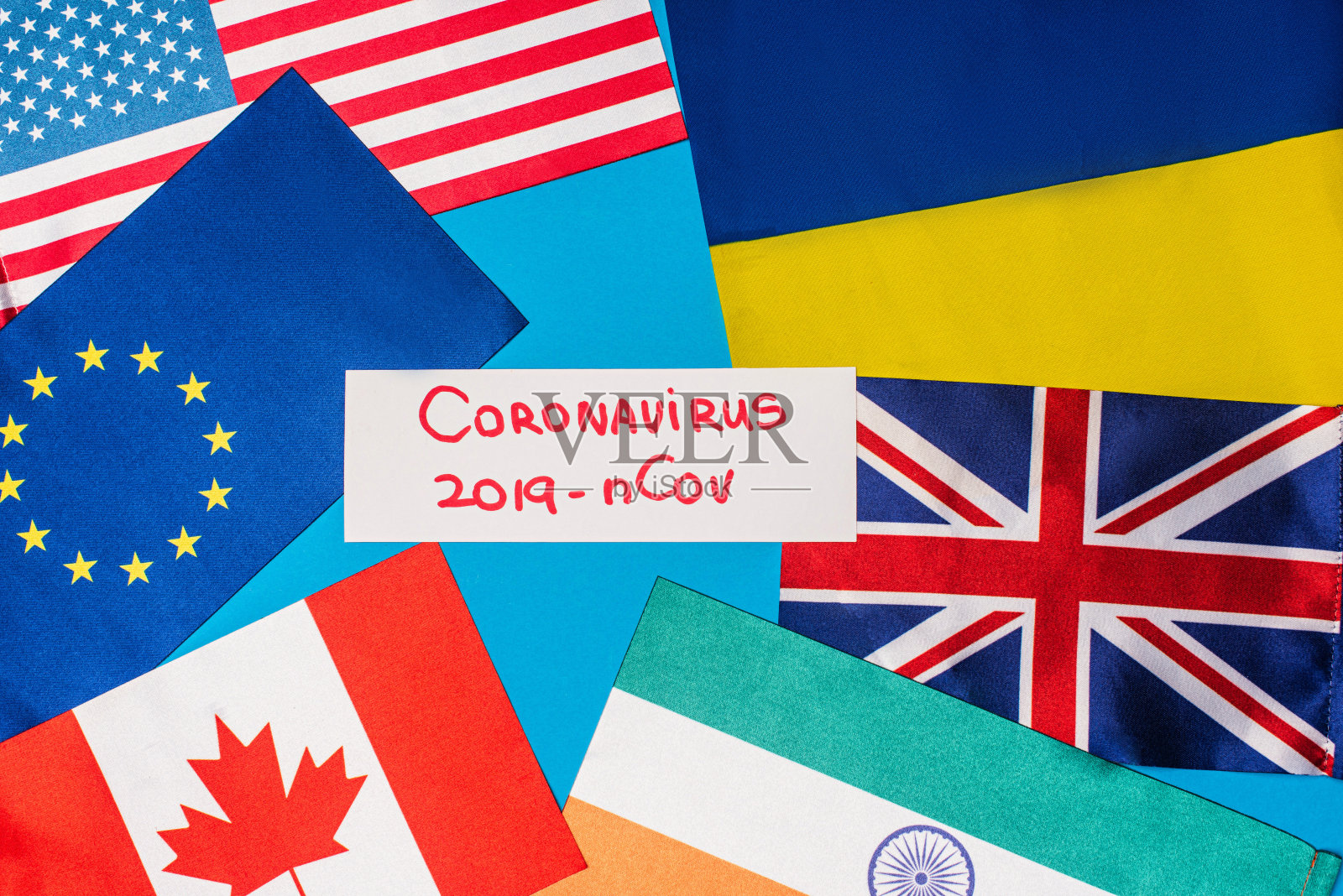在蓝色表面的各国国旗附近,俯视印有冠状病毒2019-nCov字样的卡片照片摄影图片