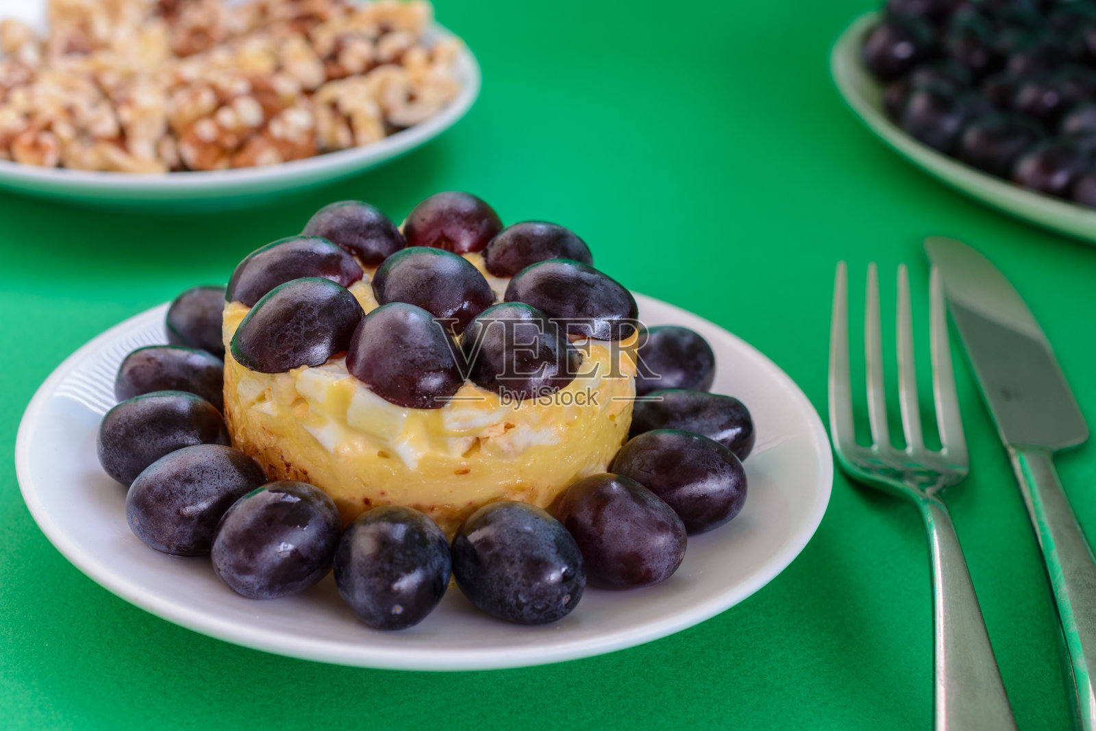 传奇的蒂凡尼沙拉在绿色的背景上分层点缀葡萄、鸡肉和奶酪。照片摄影图片