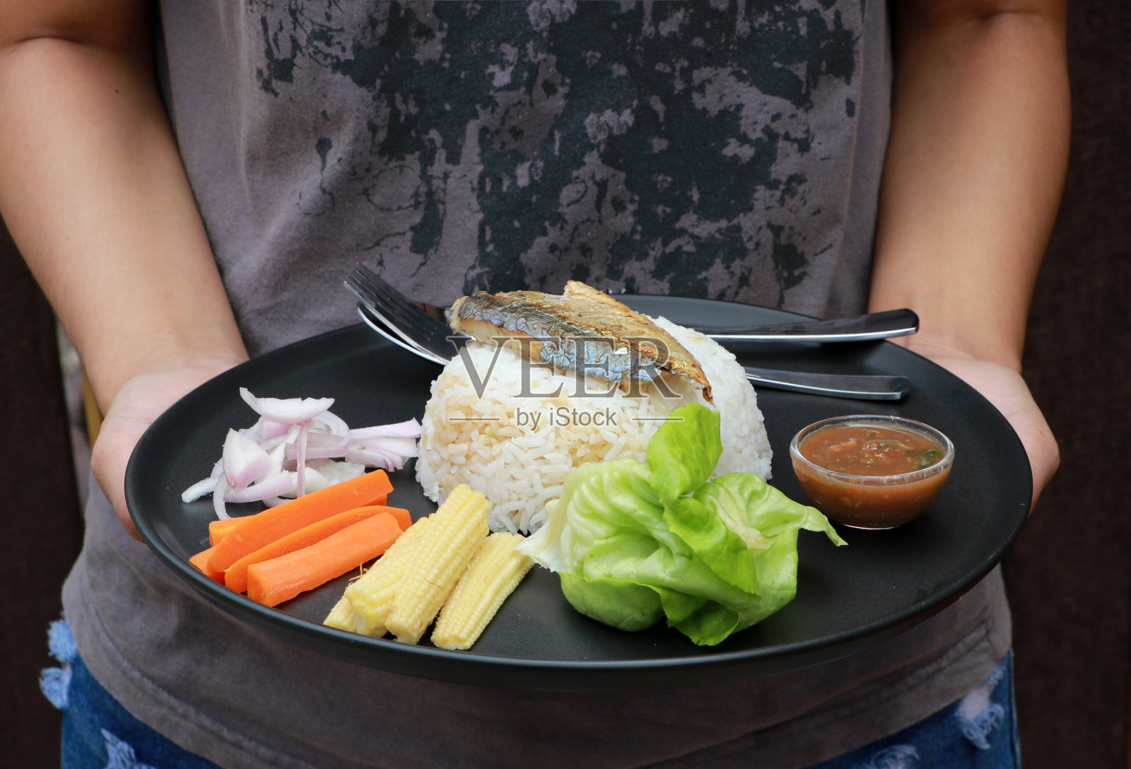 用黑色的圆盘子盛着早餐。炒鲭鱼饭配香辣虾酱和蔬菜。照片摄影图片