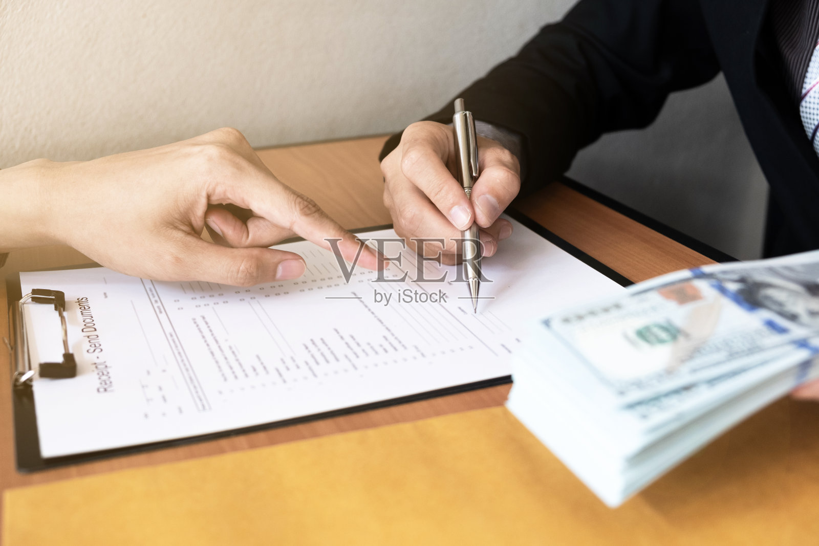 这个商人签署了一份合同协议文件,并从坐在办公室前的另一个商人那里接受了贿赂。照片摄影图片