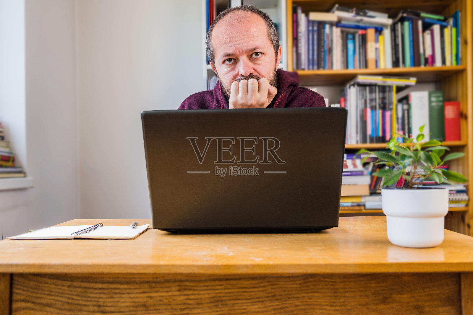 在家庭办公室里坐在笔记本电脑后面的体贴的男人照片摄影图片