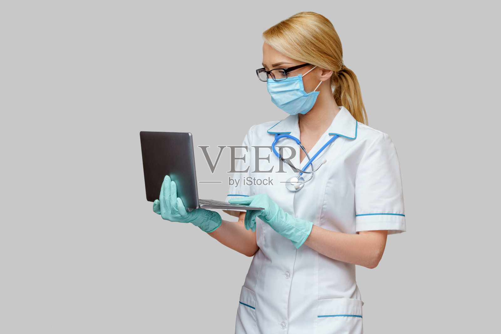 医生护士妇女戴着防护口罩和手套持有笔记本电脑照片摄影图片