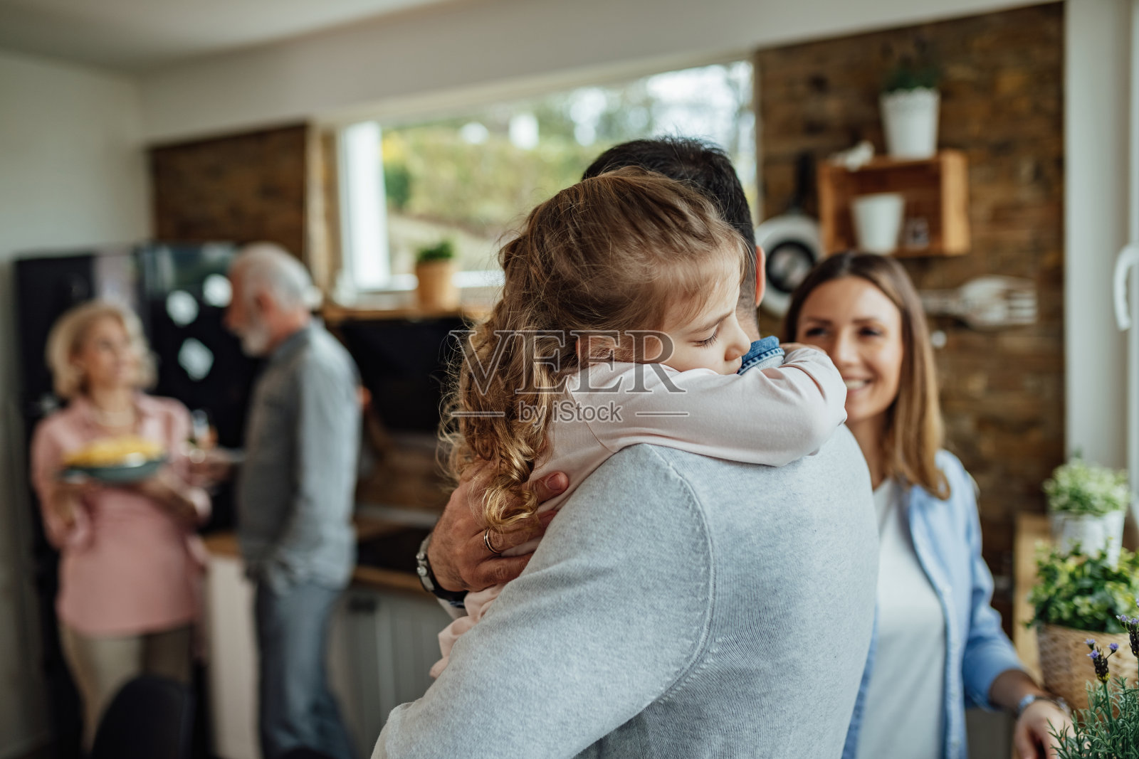 可爱的小女孩闭着眼睛享受着父亲的拥抱。照片摄影图片