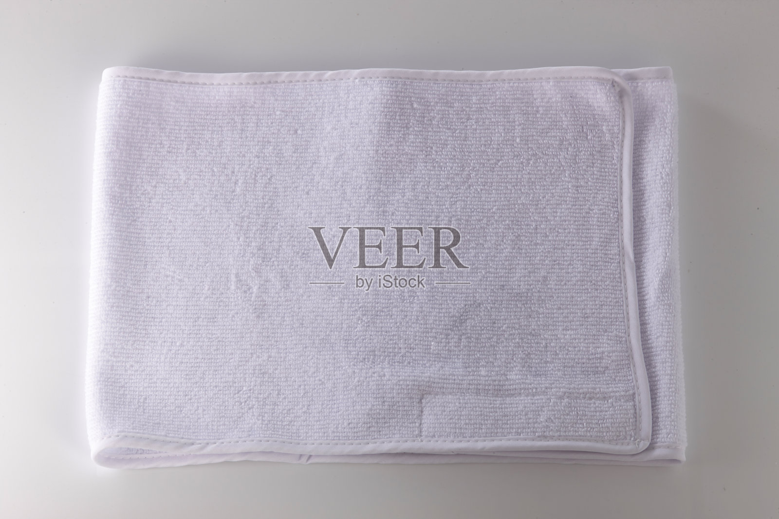 灰色背景的白毛巾。照片摄影图片