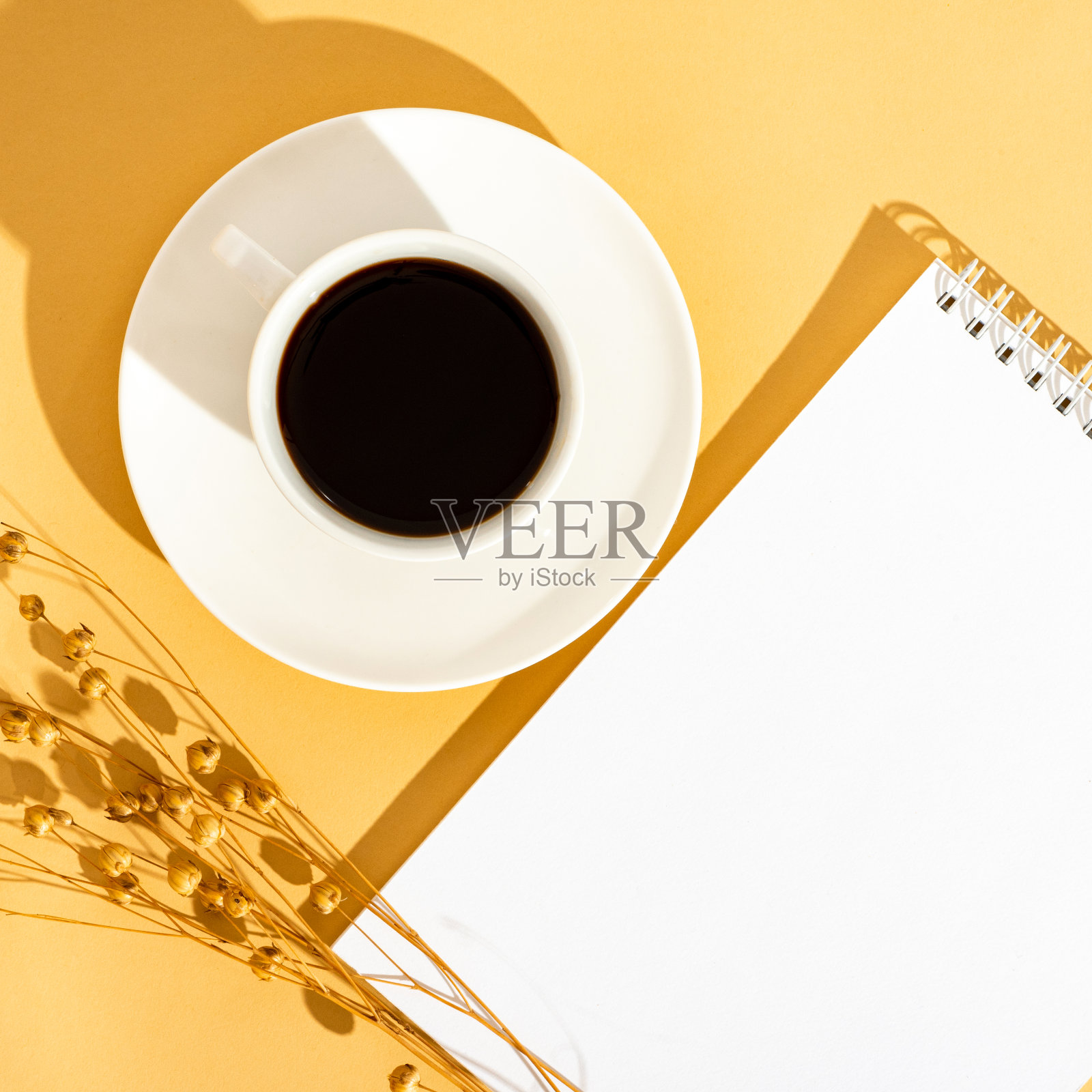 顶视图阳光橙色桌面与一个空白笔记本和一杯咖啡。照片摄影图片