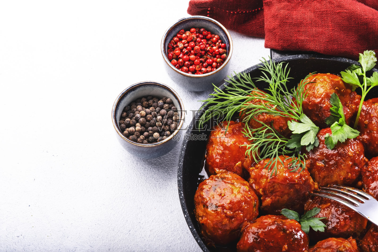 在白色的厨房桌子背景上,煎锅里放着带有番茄酱和香料的肉丸。顶部视图与复制空间照片摄影图片