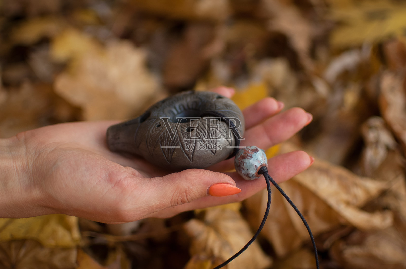 秋天的森林里,修指甲用橙色的女性手捧陶笛。轻松宁静的场景,传统的音乐理念照片摄影图片