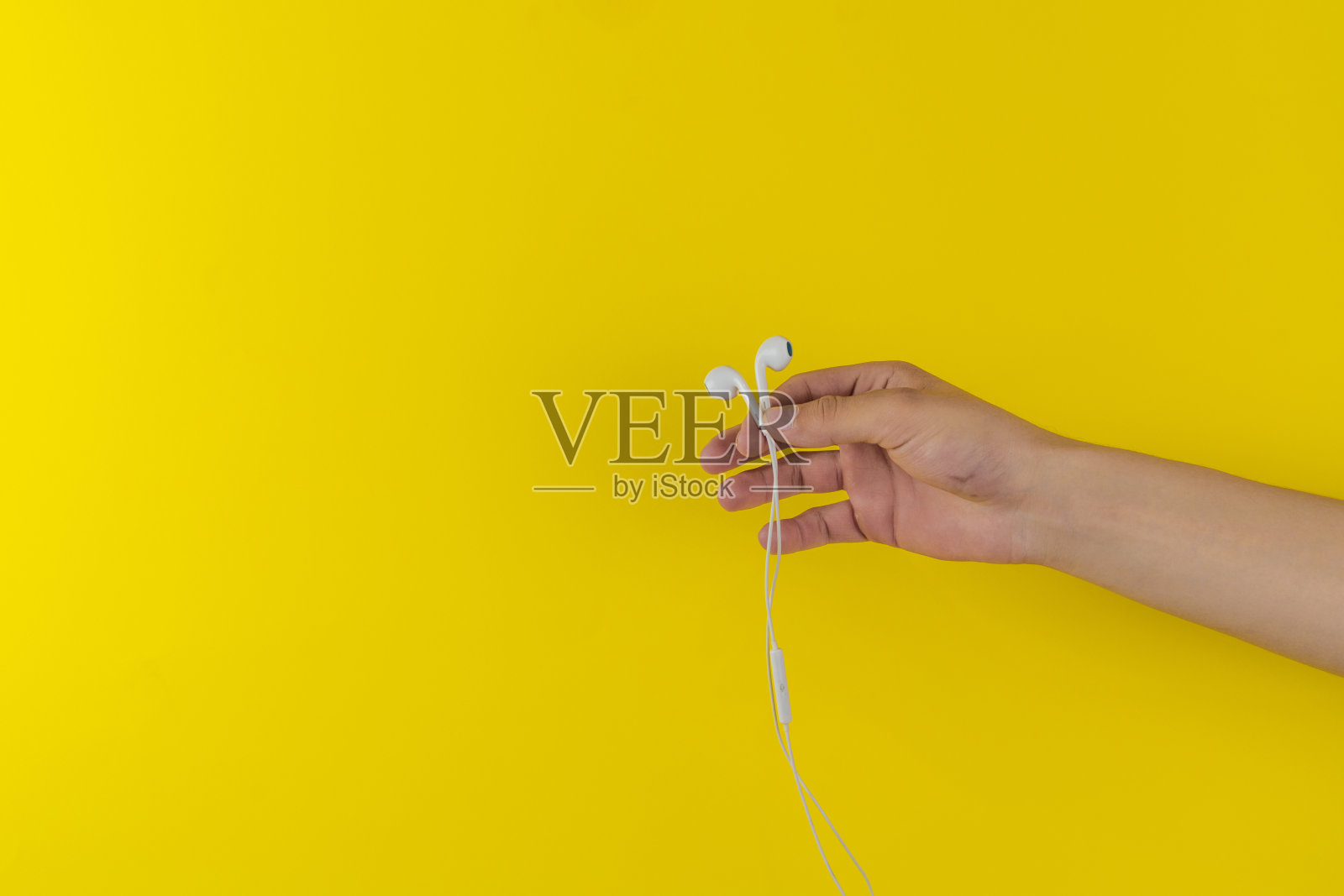 人手持便携式有线耳机或耳机隔离在多彩的背景,极简主义风格,听音乐照片摄影图片