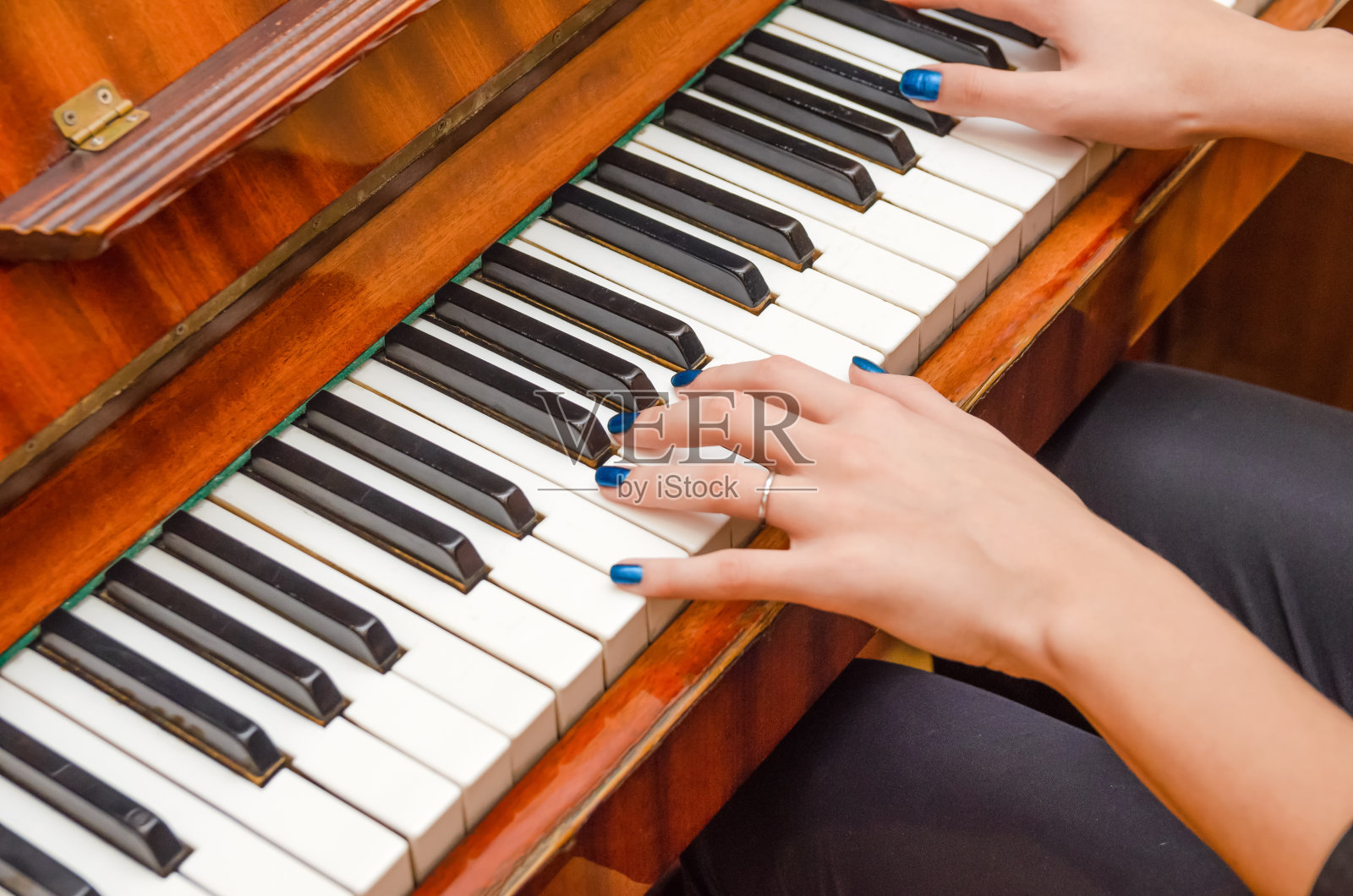 钢琴键的指甲上涂着指甲油。女孩在弹钢琴。照片摄影图片