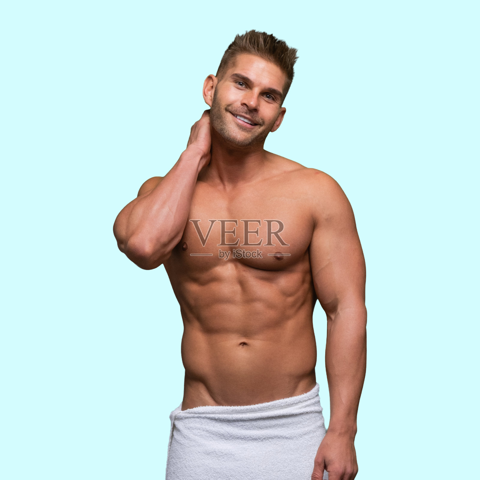 白人年轻男子站在蓝色背景下,穿着一条毛巾照片摄影图片