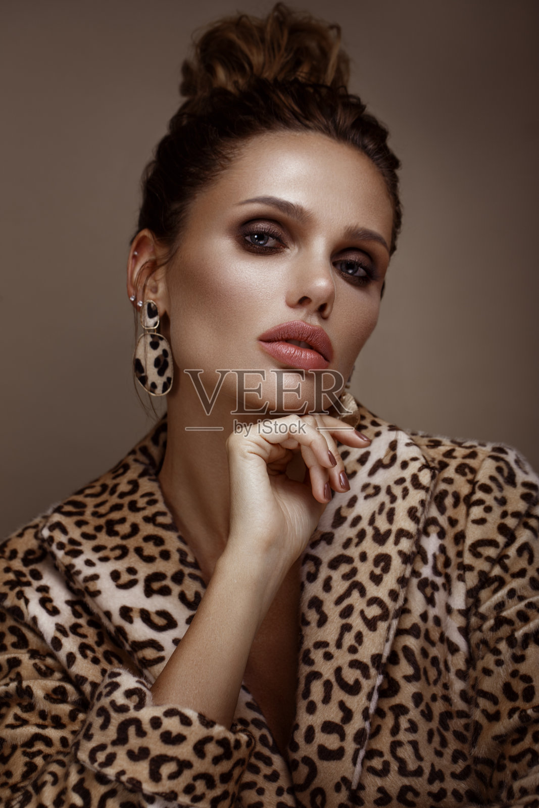 美丽性感的女人在豹纹大衣和耳环,与经典的烟熏妆和时尚的发型。美丽的脸。照片摄影图片