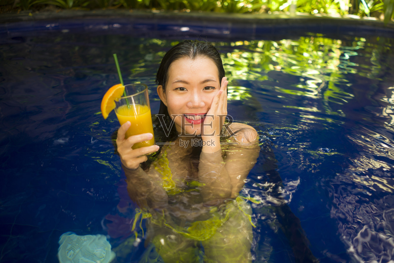 夏天的生活方式肖像年轻美丽和快乐的亚洲韩国女人穿着比基尼在游泳池享受假期放松和愉快的沐浴在别墅或豪华热带度假村照片摄影图片