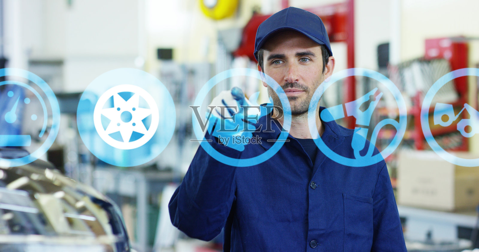 一个年轻英俊的汽车技师在一个汽车车间的肖像,而他正在使用未来的技术。照片摄影图片