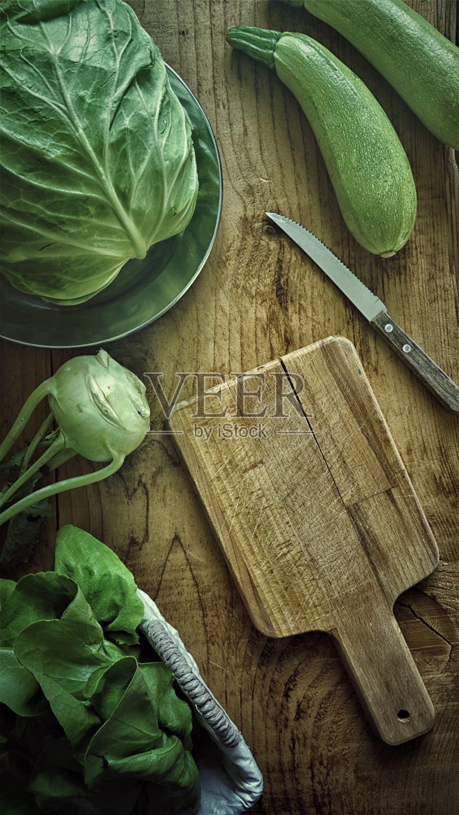 平铺新鲜的绿色蔬菜,大头菜,萝卜,卷心菜和西葫芦在木桌和木制砧板模型在低光摄影照片摄影图片