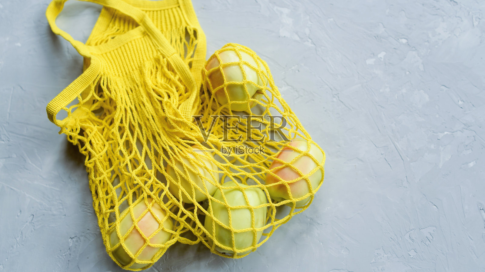 新鲜成熟的苹果装在时髦的黄色棉绳袋里。照片摄影图片