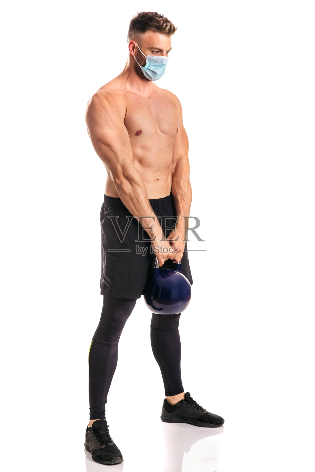 年轻的肌肉男戴着面具在工作室里锻炼照片摄影图片