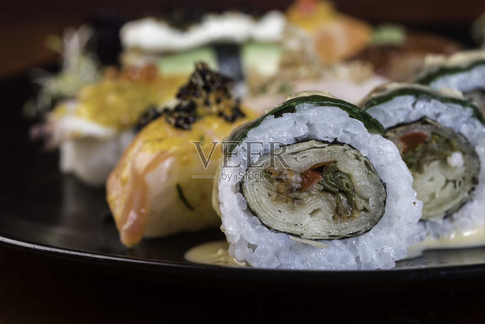 寿司佐佐酱配虾仁、芝士、黄瓜和黑鱼子酱。自制龙卷,日本料理。照片摄影图片