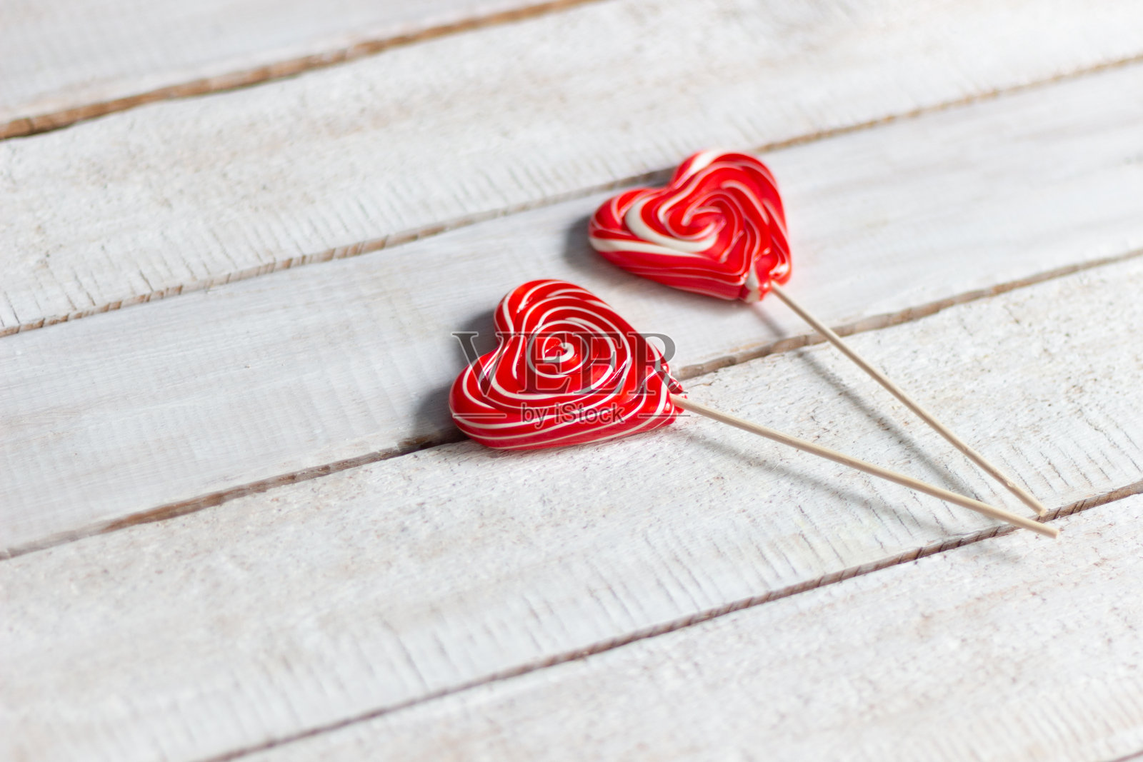 心形的红色和白色的棒棒糖在木制的背景上照片摄影图片