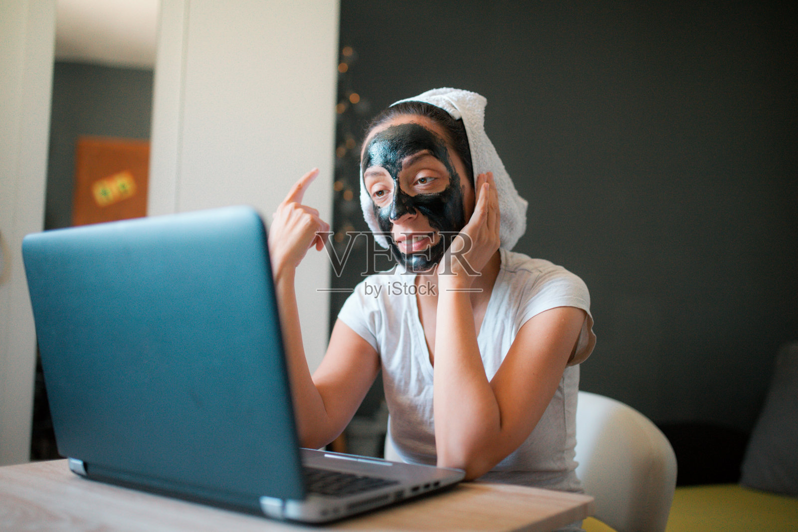 漂亮的女士在家里工作,而她的头发包裹着浴巾和面霜面膜照片摄影图片