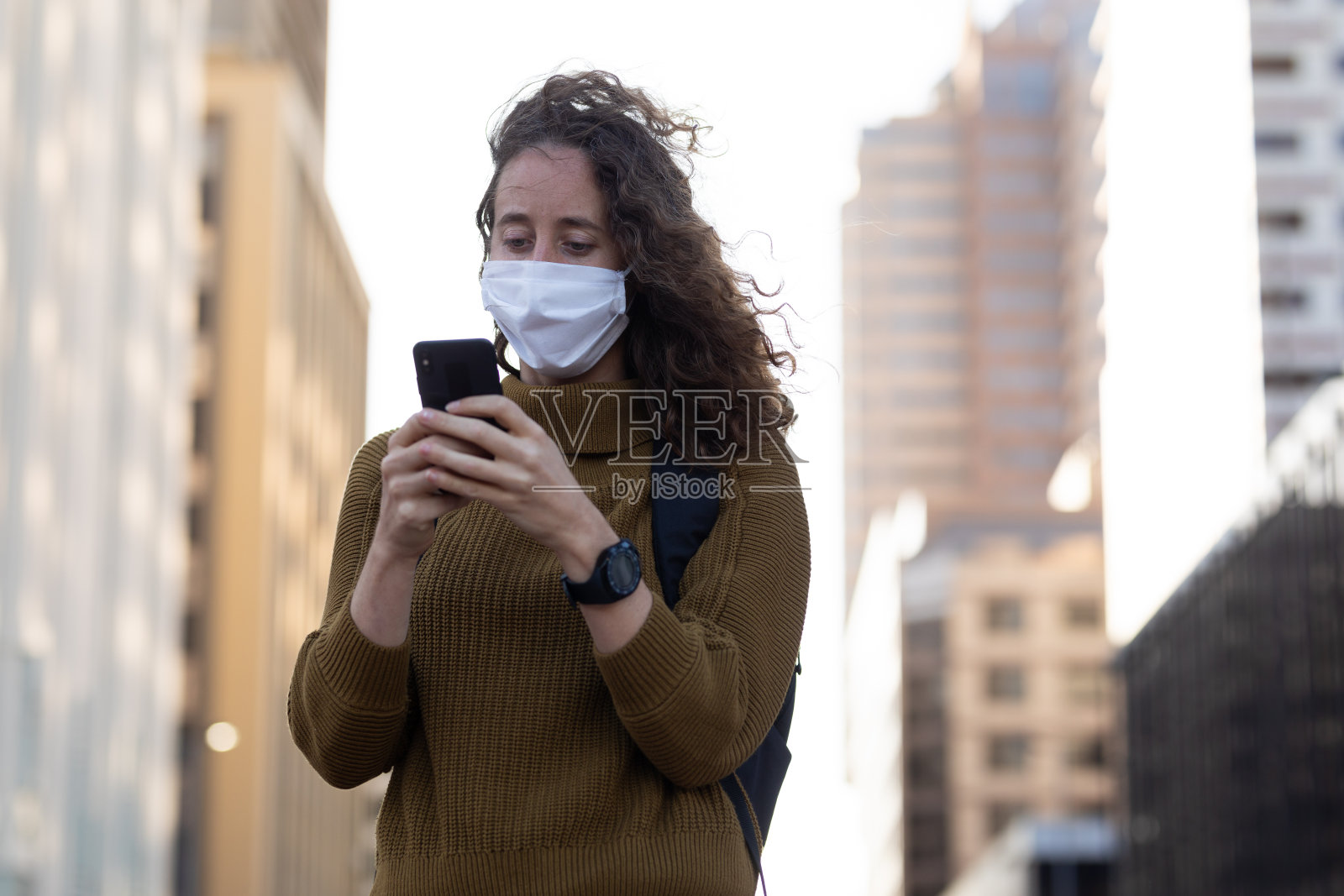 白人妇女戴着防护面具在街上用手机照片摄影图片