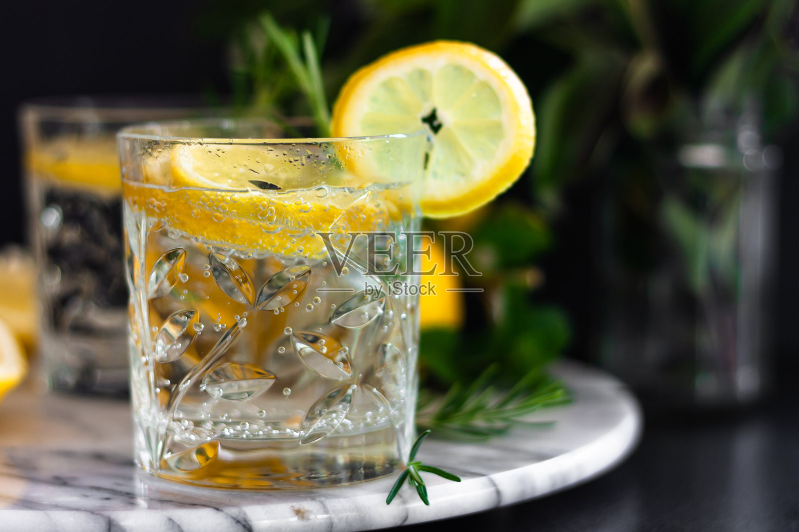 柠檬汁,柠檬莫吉托鸡尾酒,冰镇的清凉夏日饮品,用玻璃杯装,大理石托盘上放一片柠檬。侧视图。副本的空间。照片摄影图片