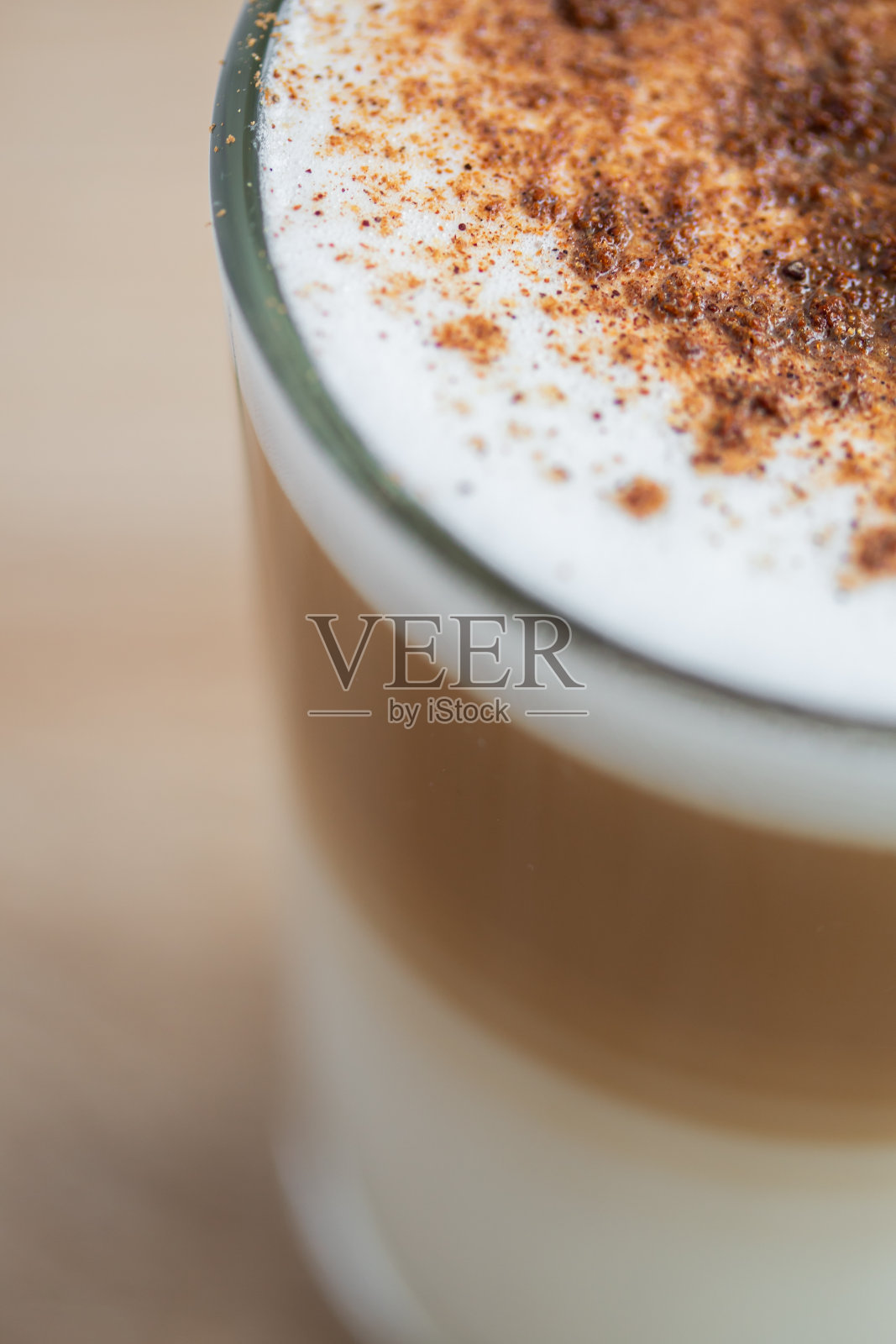 将泡沫卡布奇诺分层放入玻璃杯中,上面撒上肉桂粉。俯视图照片摄影图片