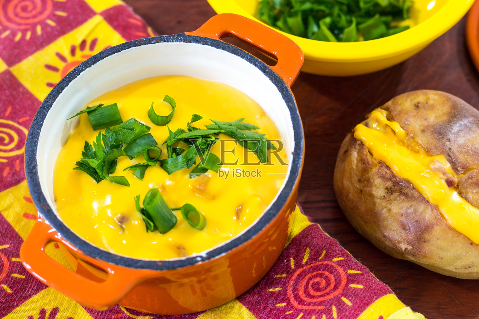 迷你橘色铁砂锅,配上融化的切达干酪、培根、韭菜和填充的烤土豆照片摄影图片