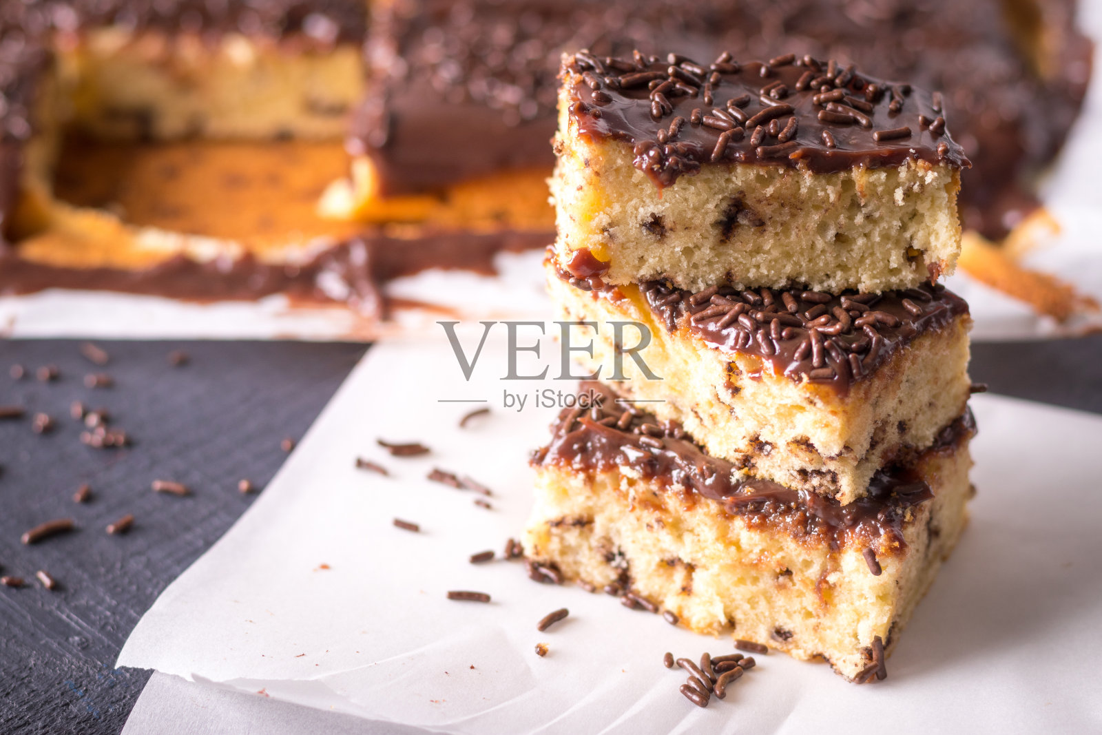 烤纸上有牛奶巧克力糖霜和Brigadeiro糖屑的麻刺蛋糕照片摄影图片