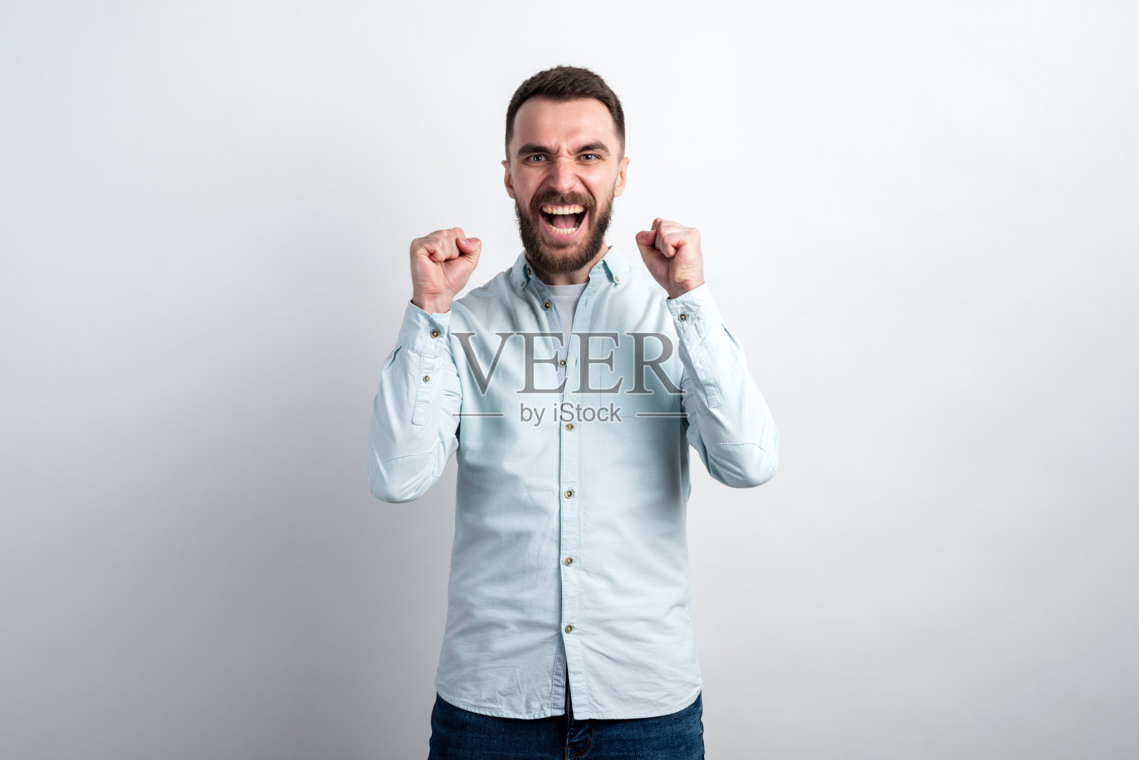 年轻人非常高兴和兴奋,举起手臂,握紧拳头的手势表示胜利或成功照片摄影图片