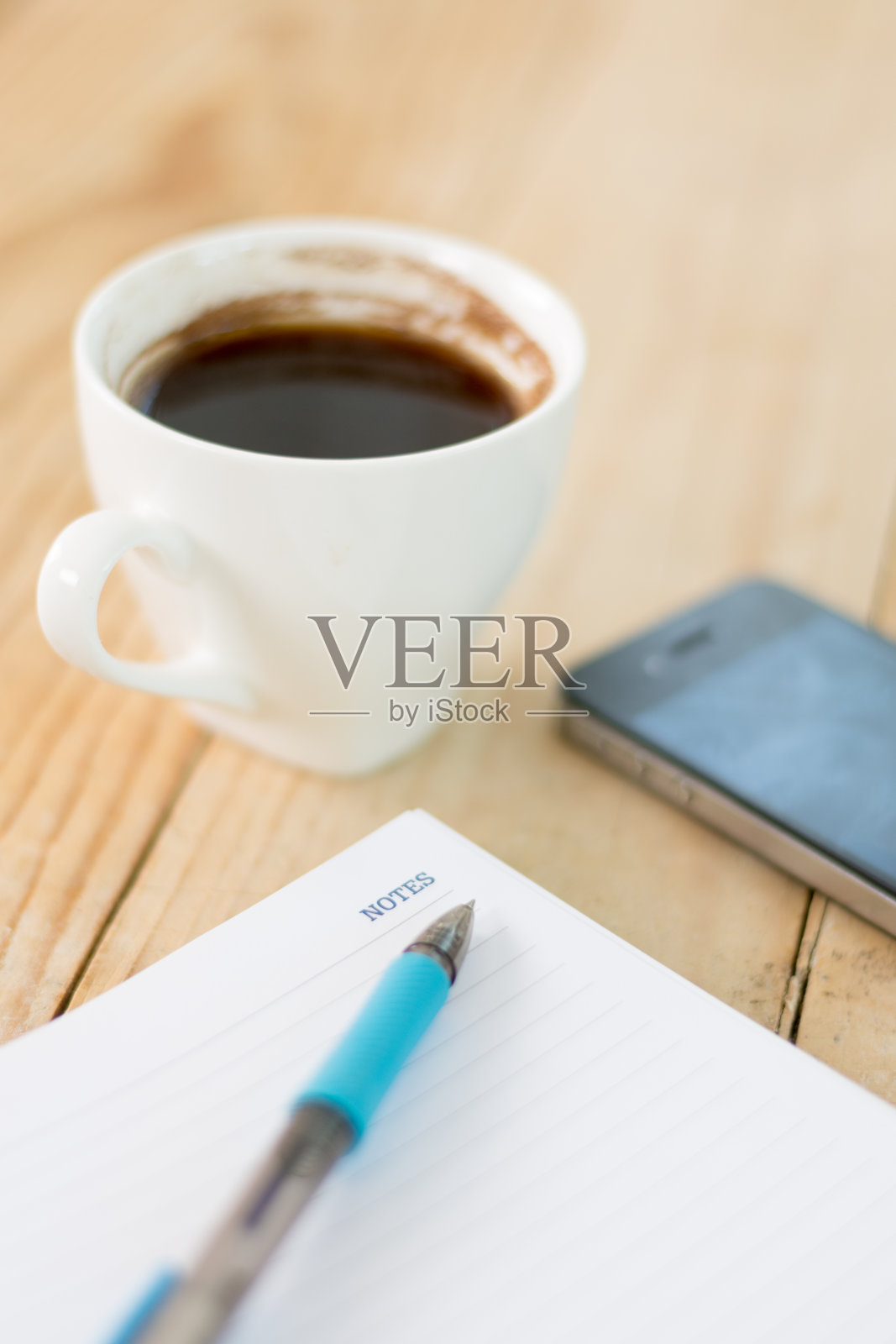 用笔在备忘录上作文字注释,咖啡放在木制背景上照片摄影图片