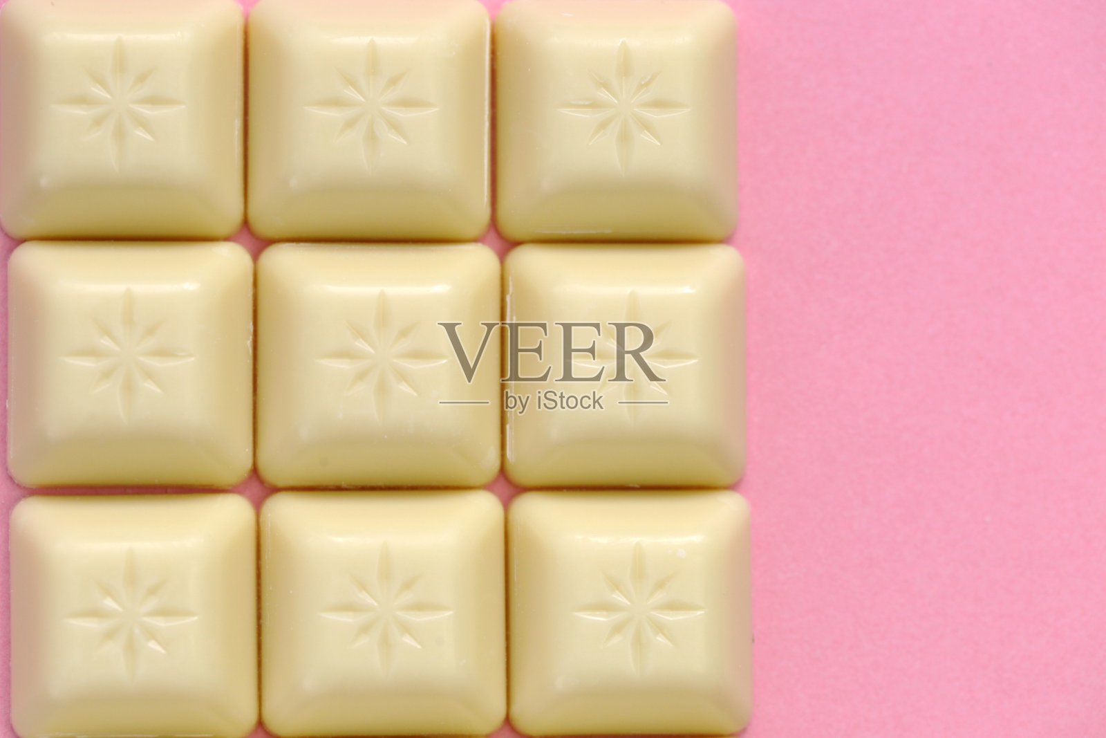 浅粉色背景上的白巧克力棒。照片摄影图片