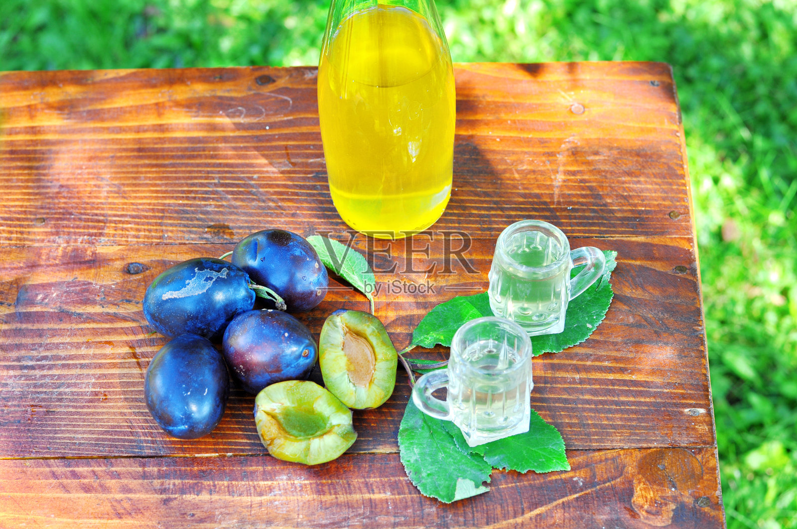 这是一款著名的李子白兰地,用小酒杯盛着李子,放在果园的木桌上。塞尔维亚传统品牌有机生产的酒精饮料照片摄影图片