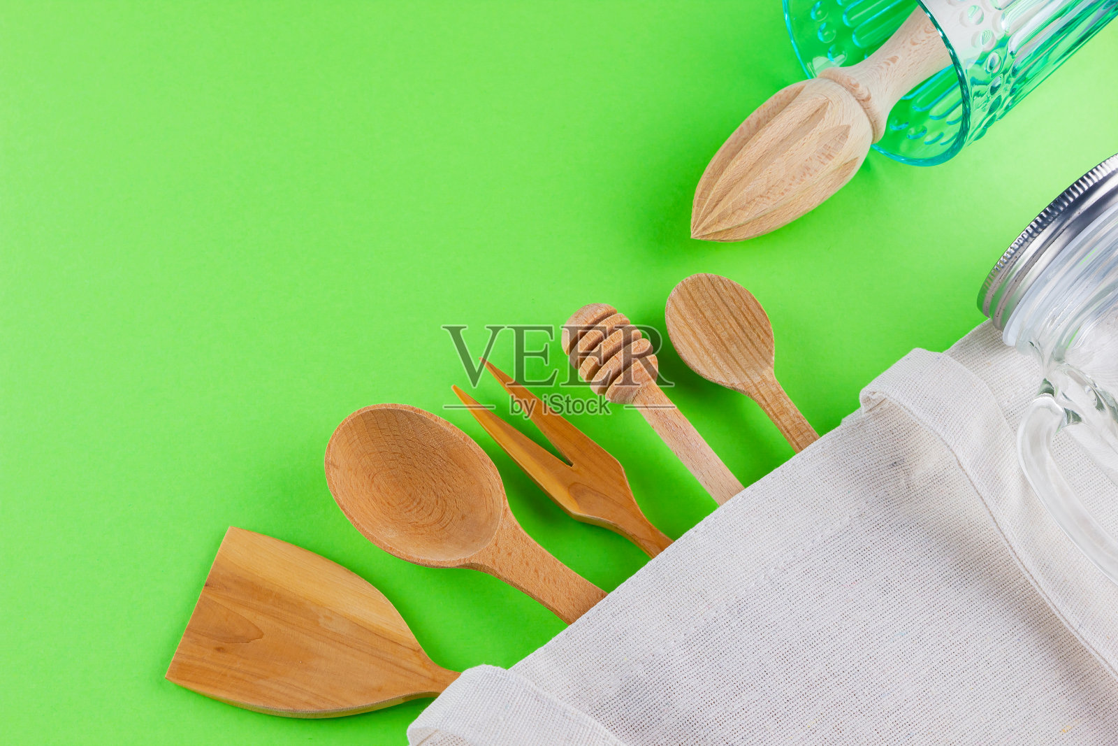 “零浪费”的概念。棉环保袋,玻璃和木制餐具在绿色的背景。一套环保木制餐具。塑料自由概念。极简主义。前视图。本空间照片摄影图片