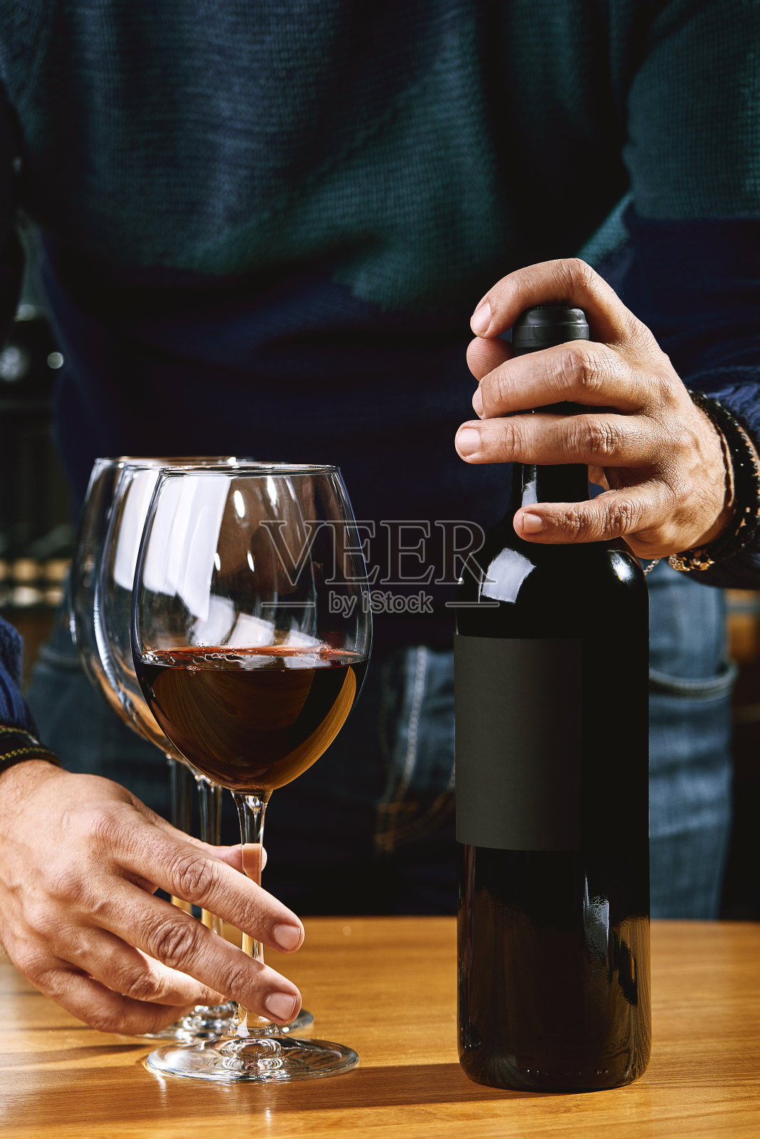 侍酒师将手伸进镜框,将葡萄酒倒入杯中。酿酒,喝酒的文化照片摄影图片