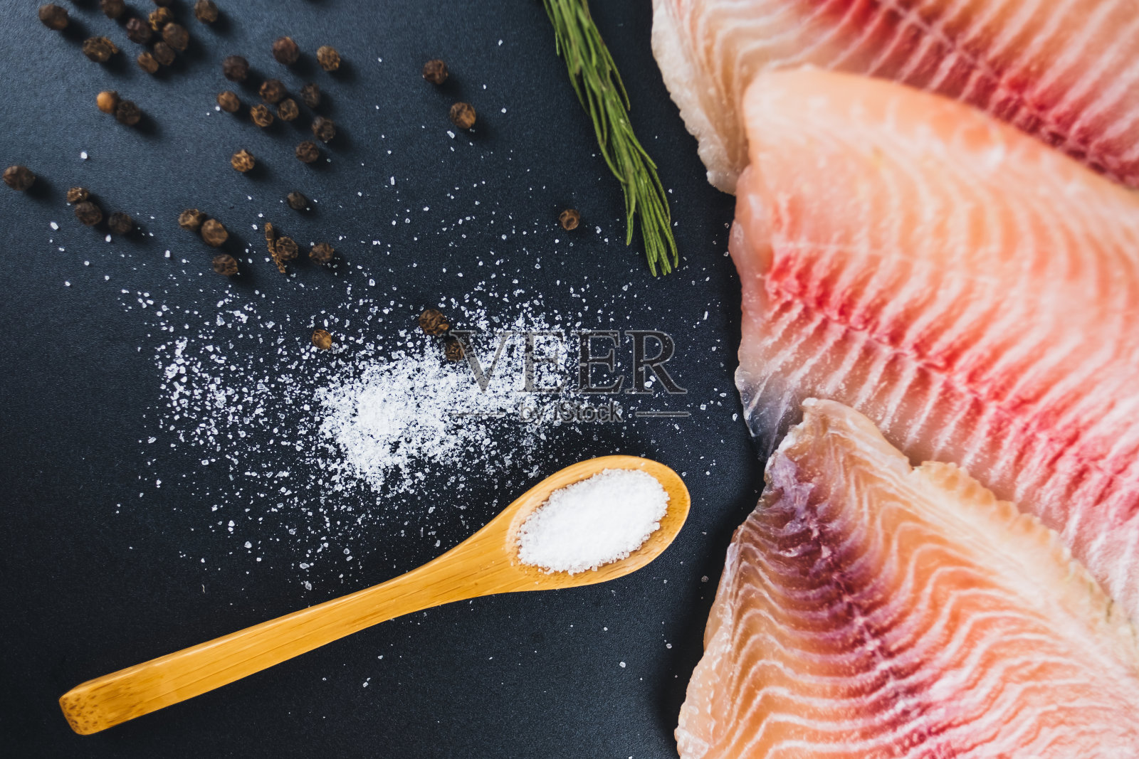 新鲜的白色罗非鱼片,以黑色为背景。照片摄影图片