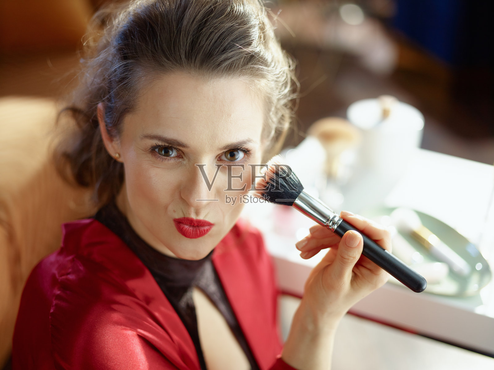 时髦的女人在阳光明媚的日子用化妆刷在现代家庭照片摄影图片