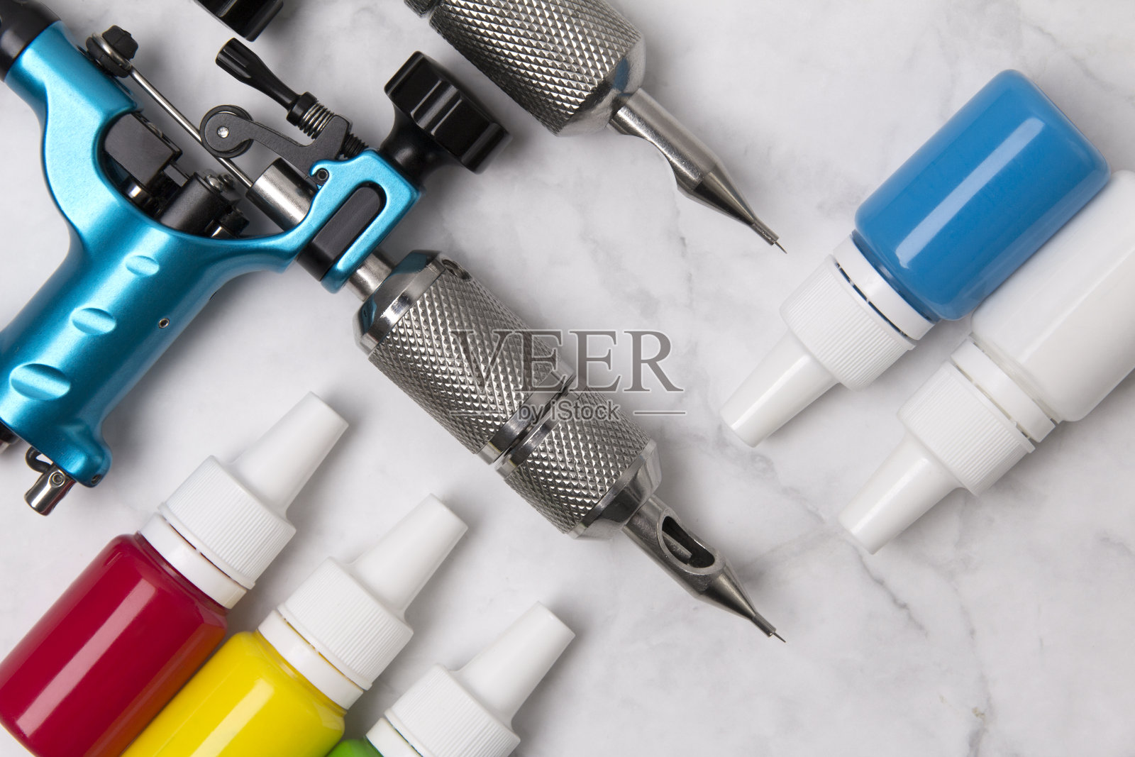 纹身大师工作场所:白色大理石背景上的纹身机和各种墨水照片摄影图片