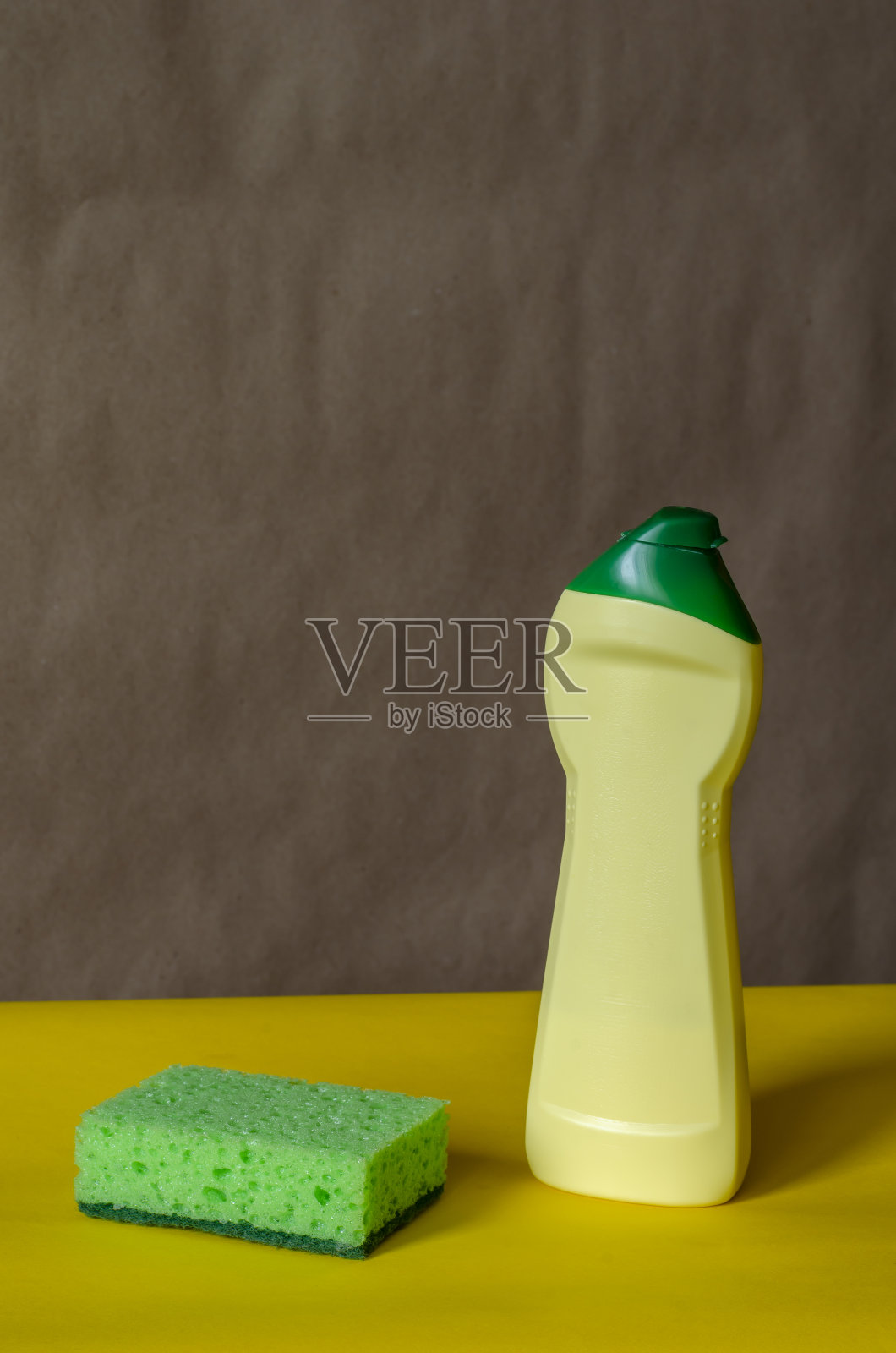 演示一个清洁的家用化学品容器和一个绿色厨房海绵。照片摄影图片
