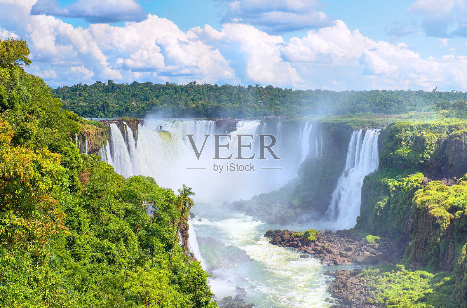 阿根廷的伊瓜苏瀑布,从魔鬼之口看。许多雄伟有力的瀑布与雾的全景。全景图像与蓝天与云的反射。照片摄影图片