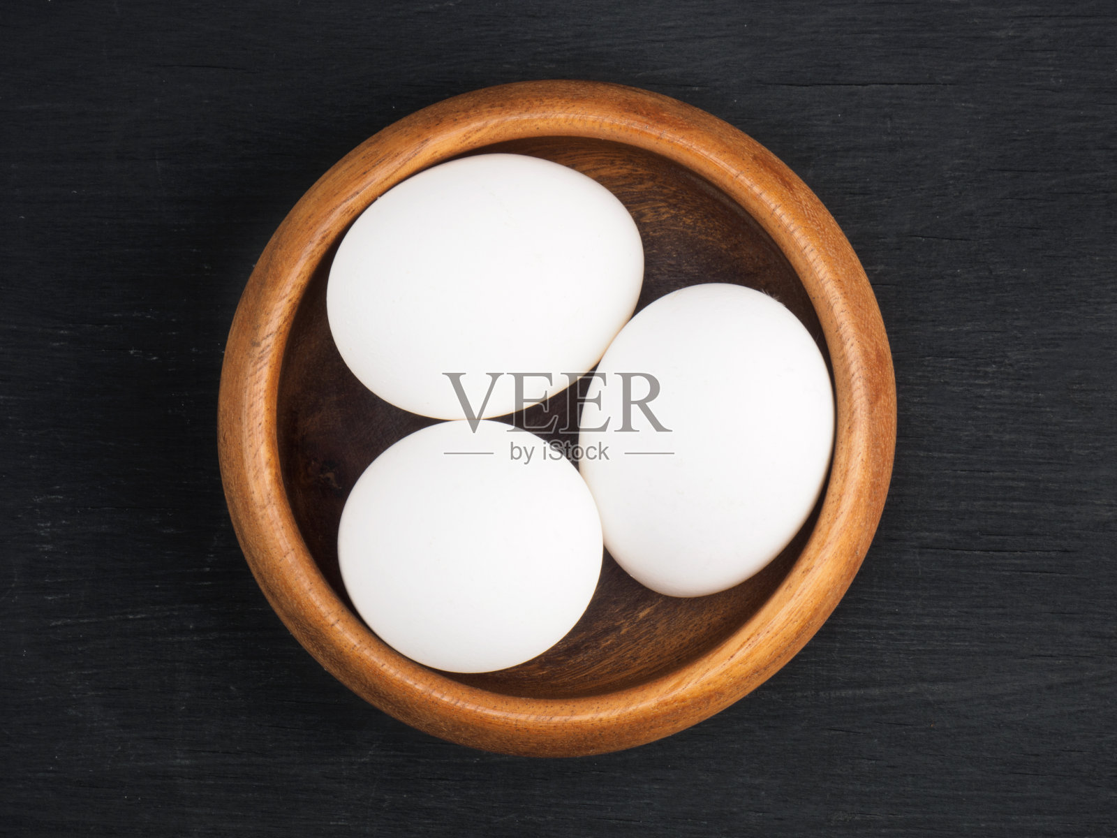 生鸡蛋在木碗上的黑色木制背景与复制空间。有机食品的概念照片摄影图片