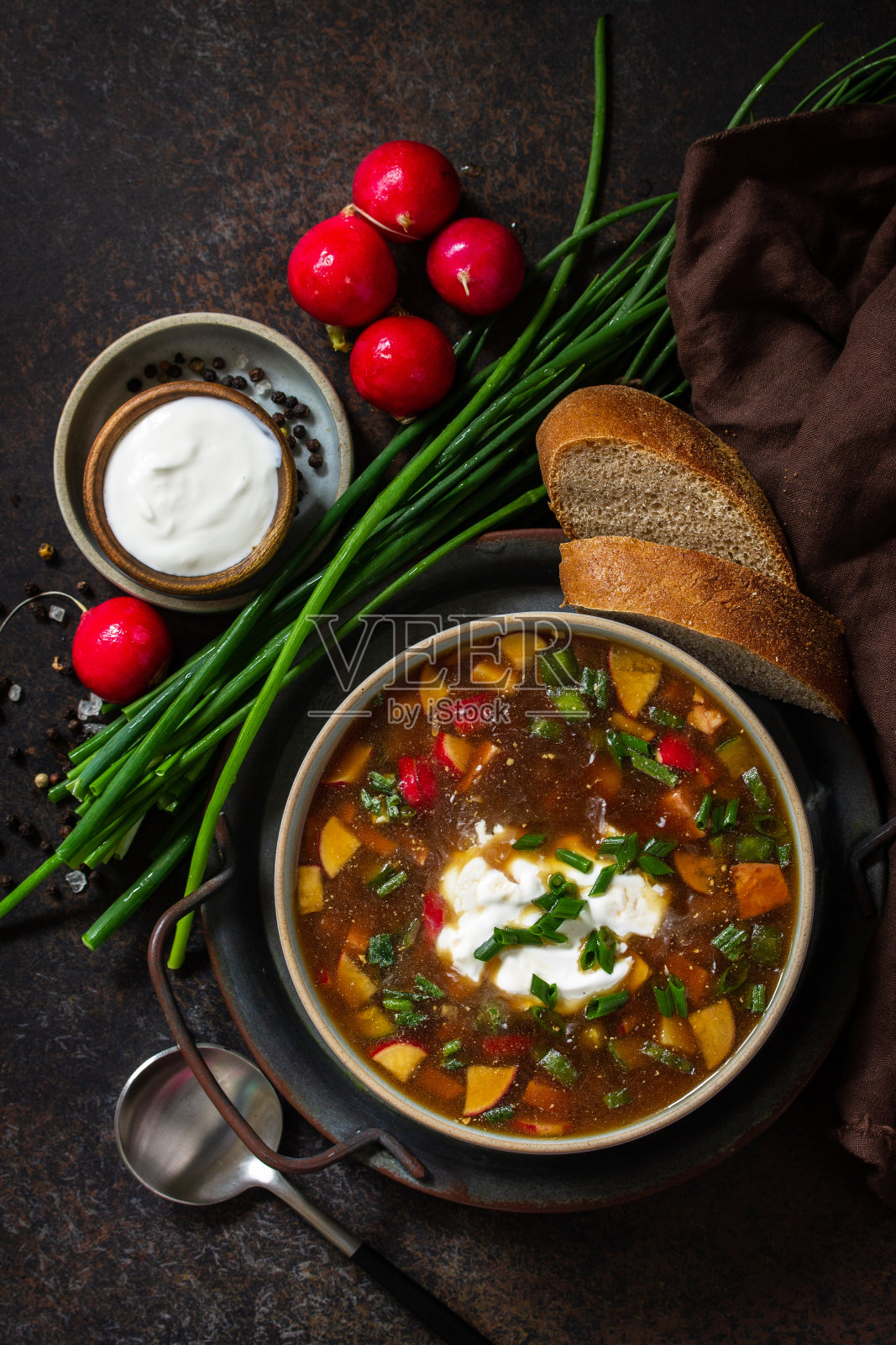 俄罗斯传统菜肴。在寒冷的夏天,深色的石头台面上的碗里盛着克瓦斯、香肠和蔬菜的欧克罗斯卡汤。俯视图平铺背景。照片摄影图片