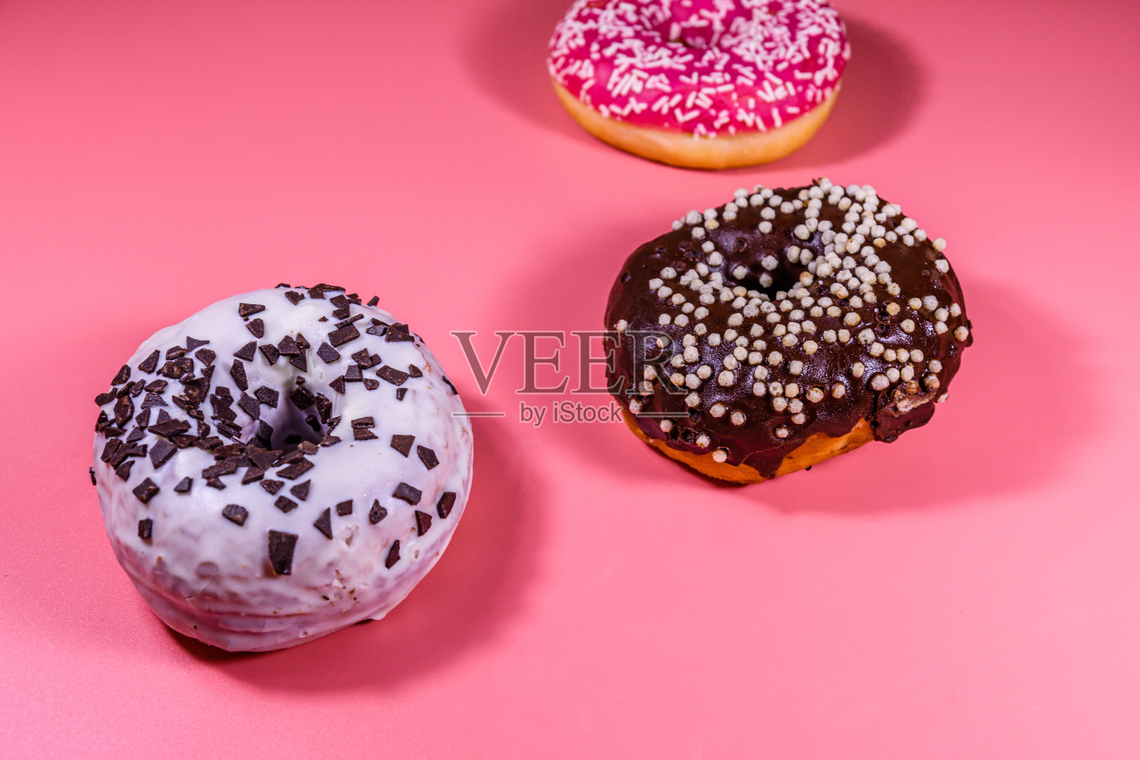 鲜亮的甜甜圈孤立在粉红色的背景上照片摄影图片