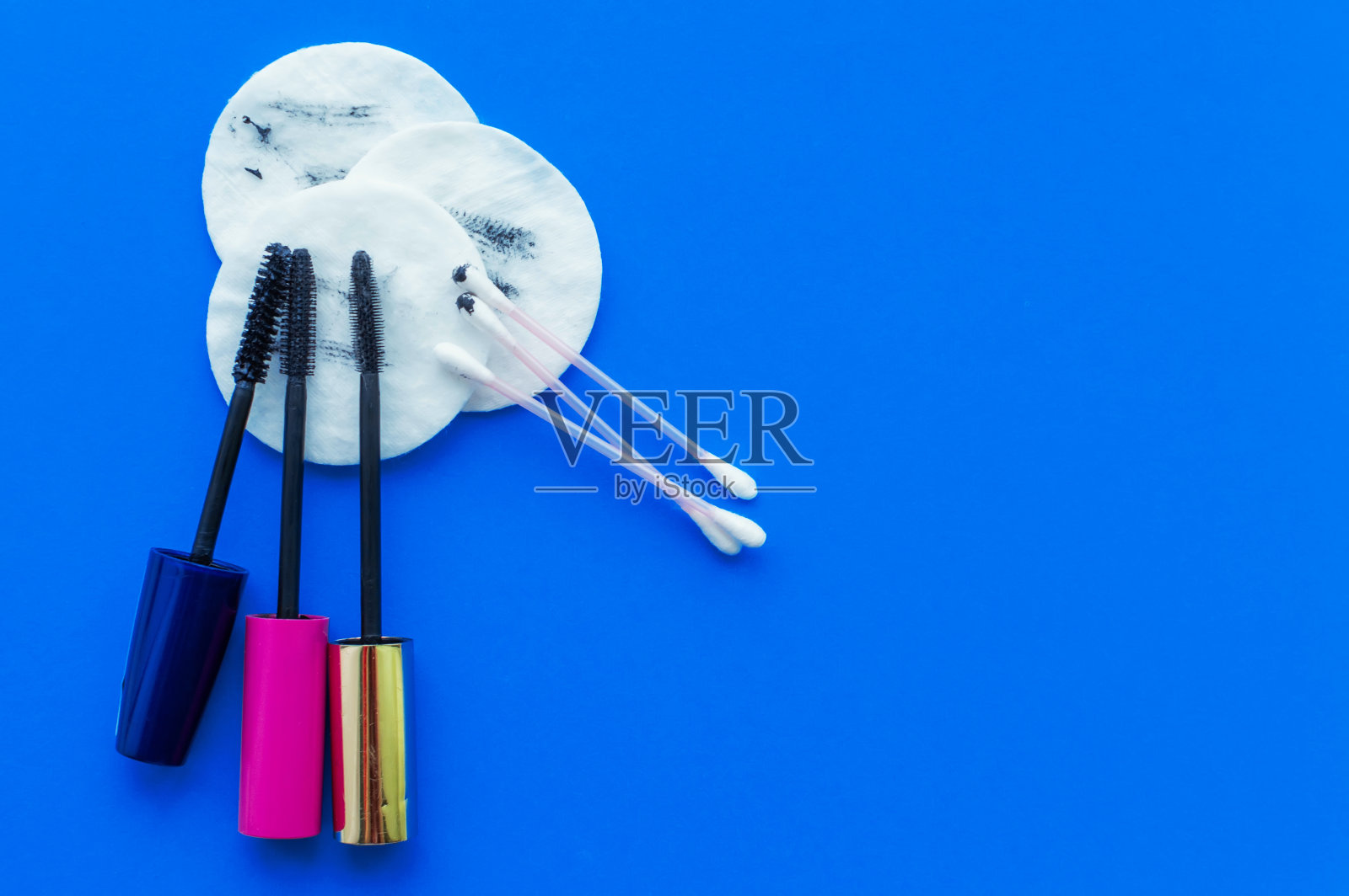 用脏的化妆棉、睫毛膏刷和棉签在有书写空间的蓝色背景上卸妆照片摄影图片