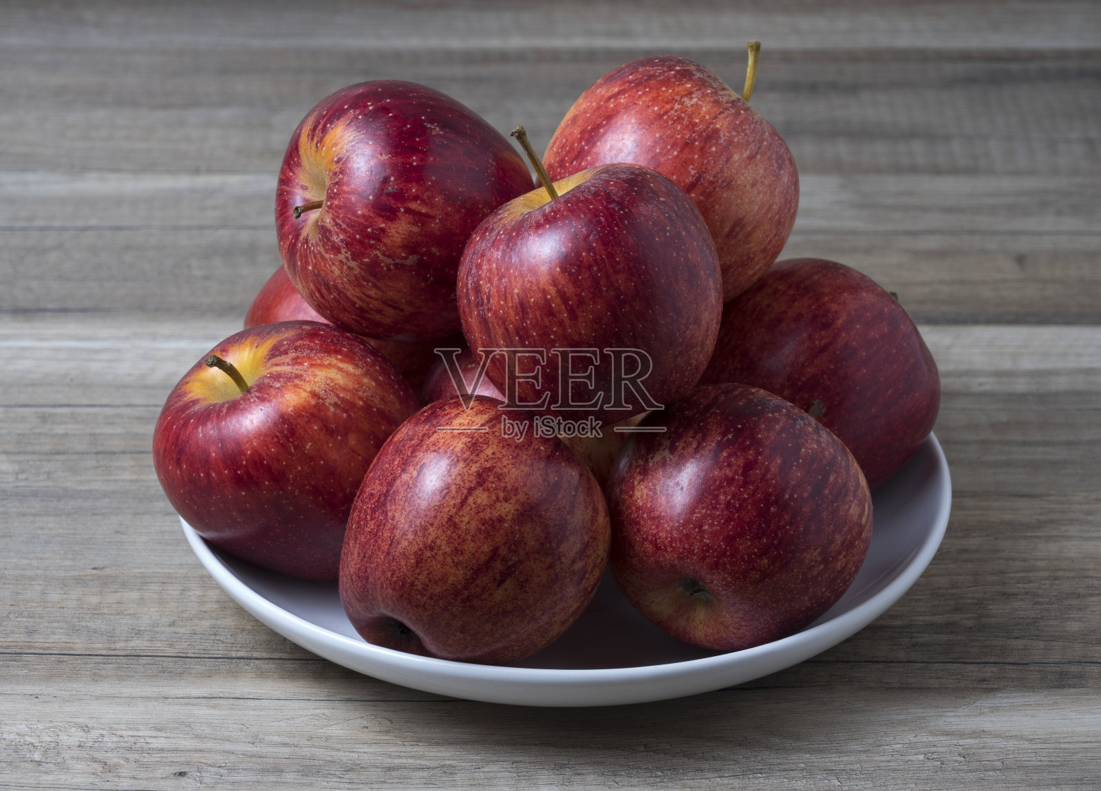 新鲜多汁成熟的红苹果在碗上木制的白色桌子。照片摄影图片