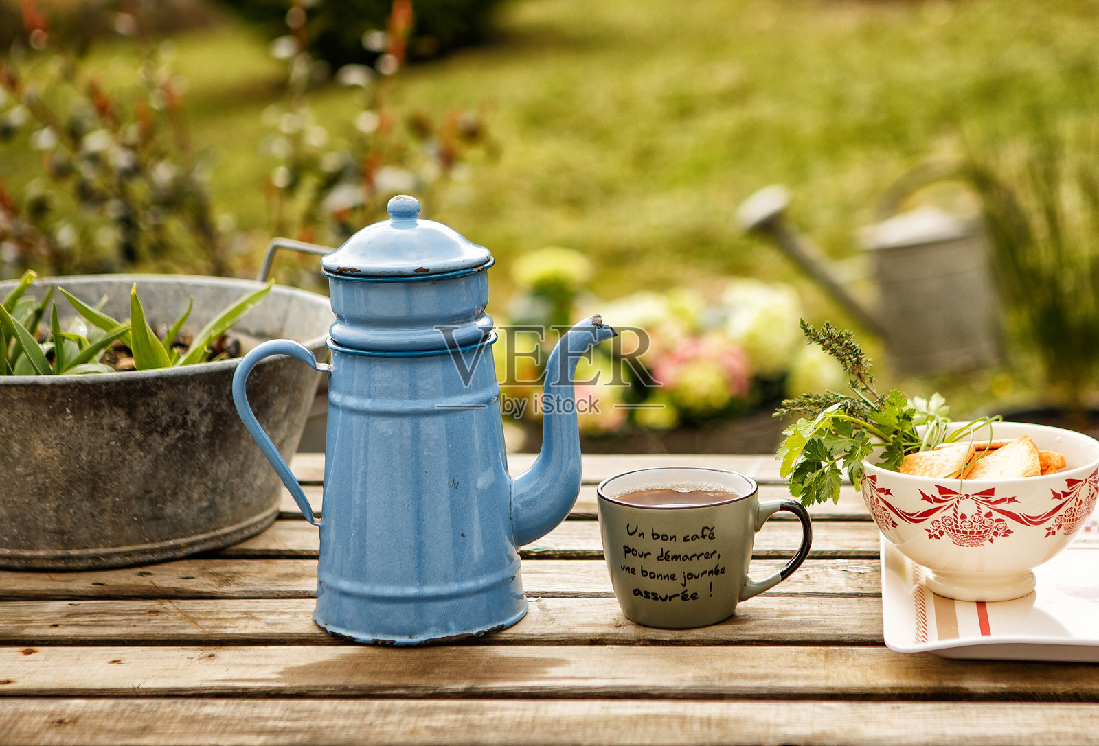 从老茶壶中取出茶,倒入马克杯。普罗旺斯。照片摄影图片