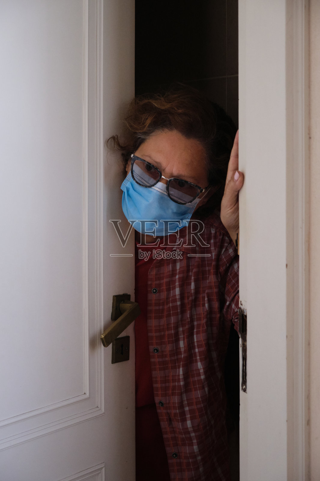 一个女人戴着面具从门口往外看照片摄影图片