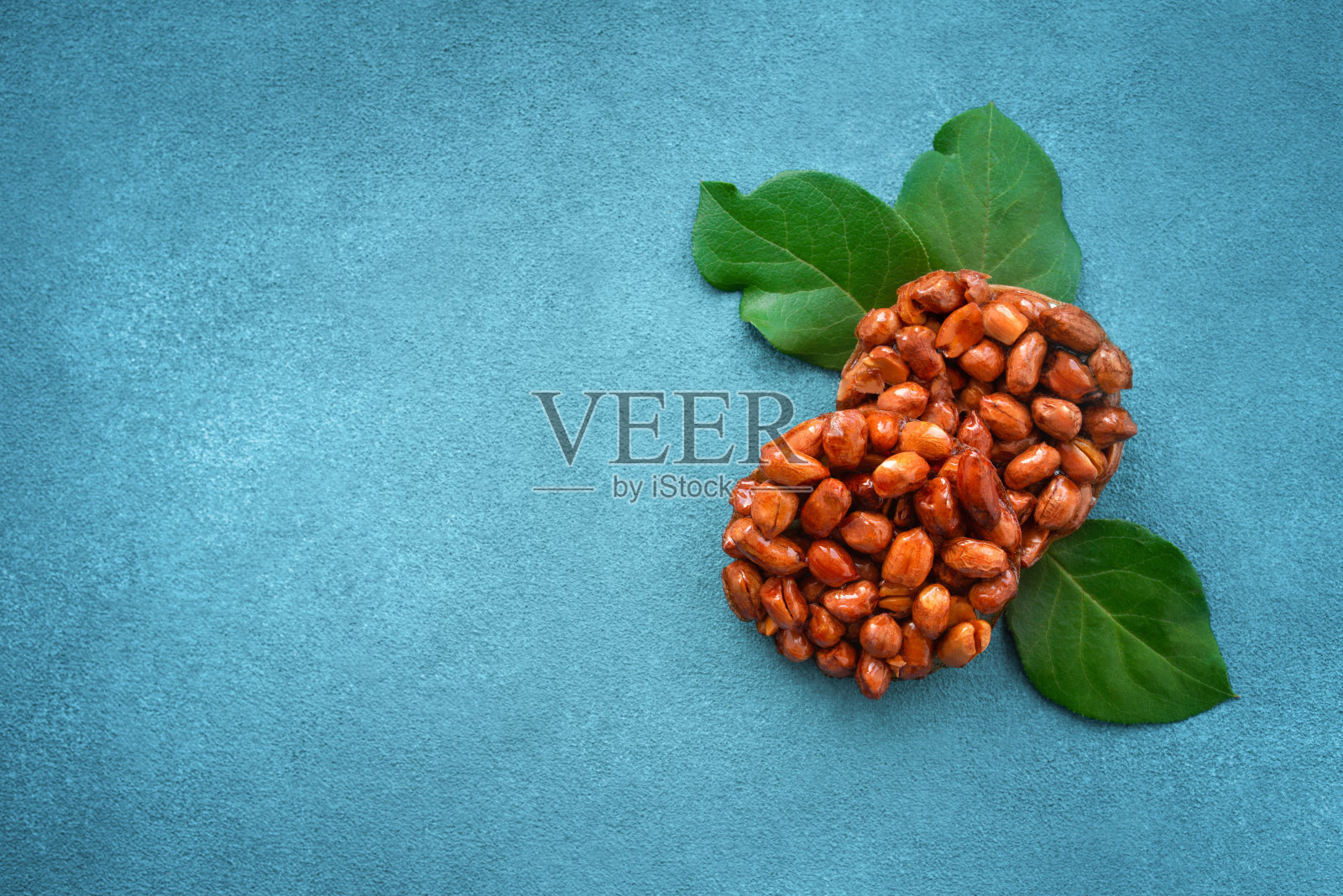 由花生、蜂蜜和蓝色背景上的天然树枝制成的美味的东方糖果。照片摄影图片